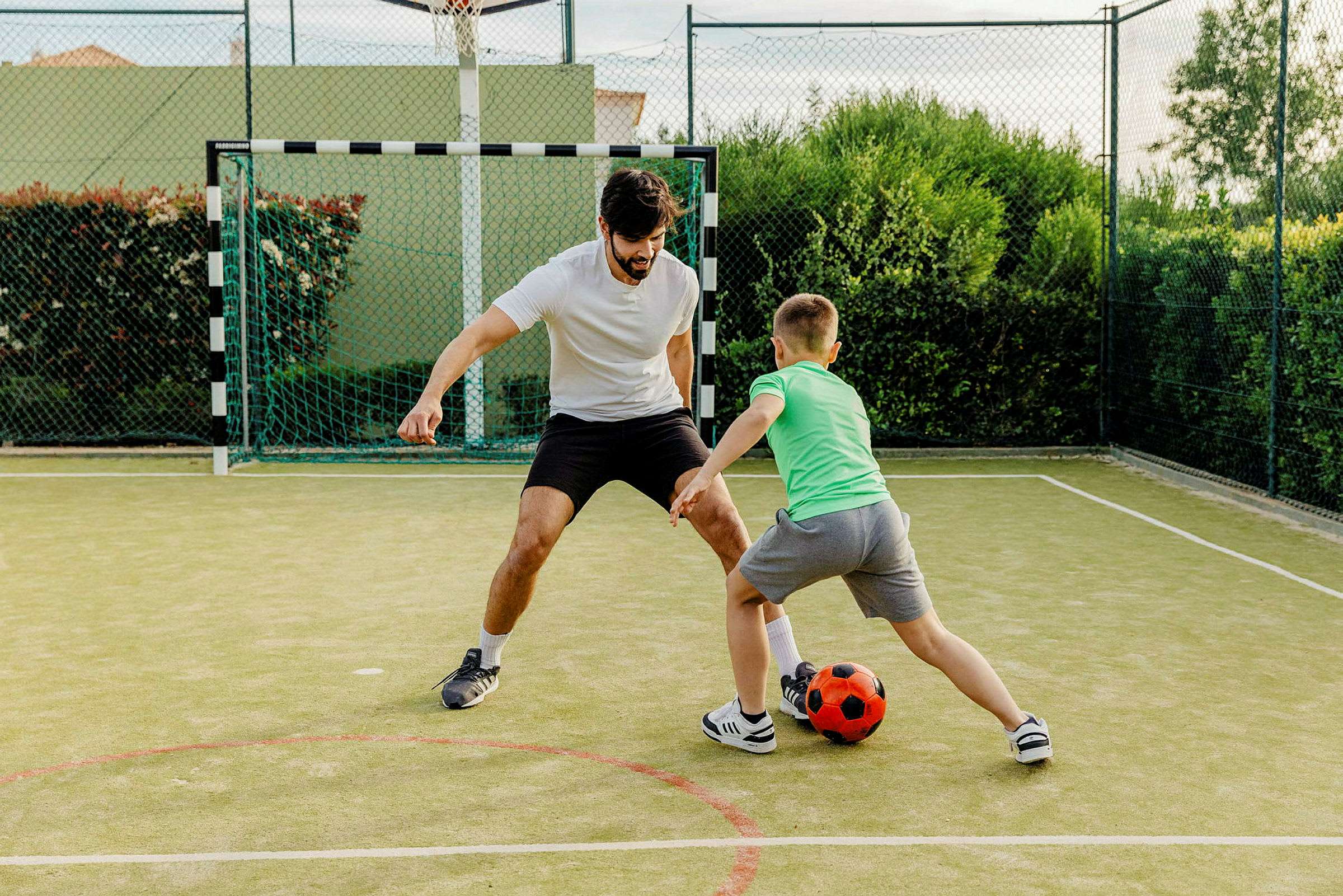 To personer spiller fotball på en liten kunstgressbane. (AI-generert tekst)