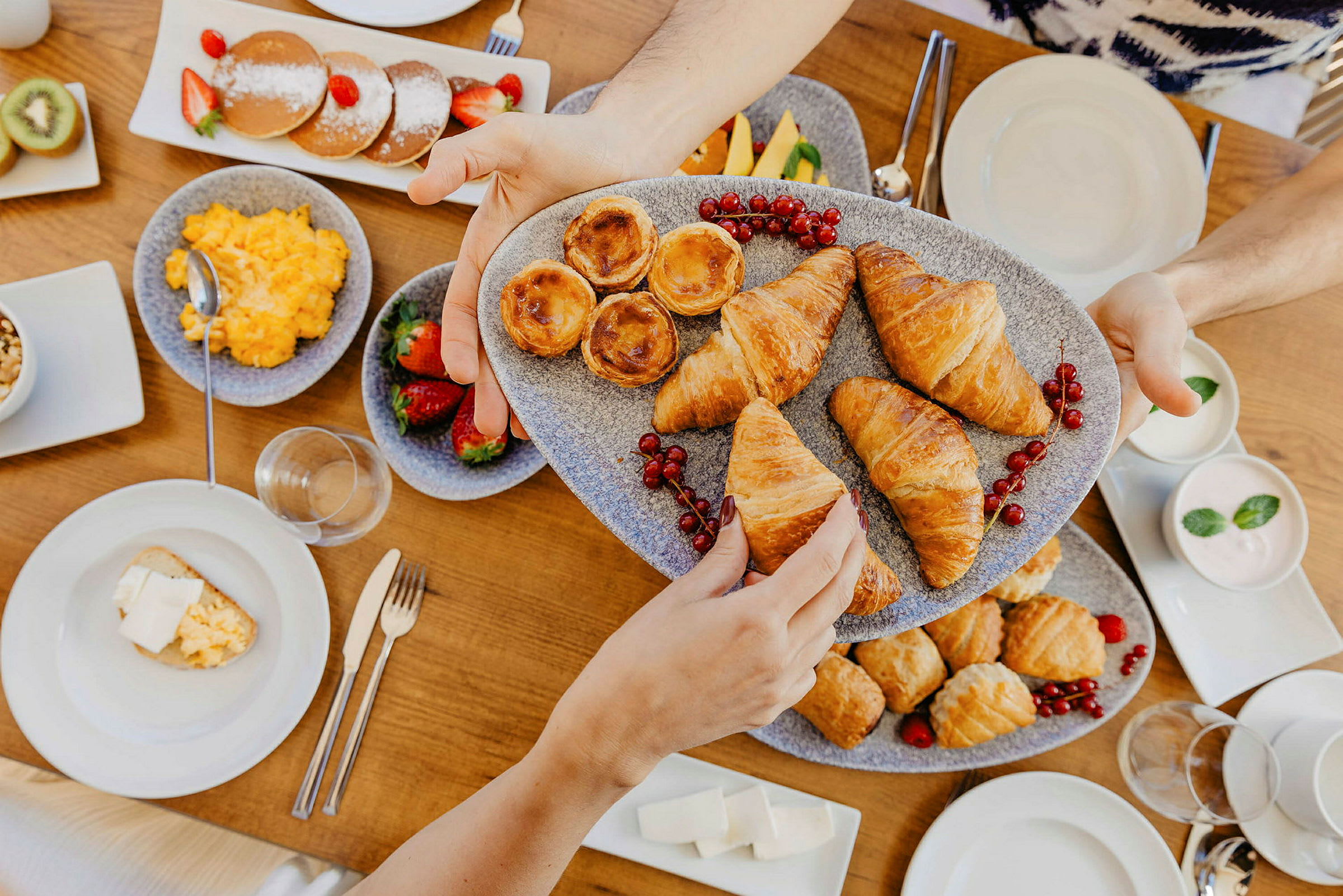 En frokost med forskjellige bakverk, frukt og andre retter servert på et bord. (AI-generert tekst)