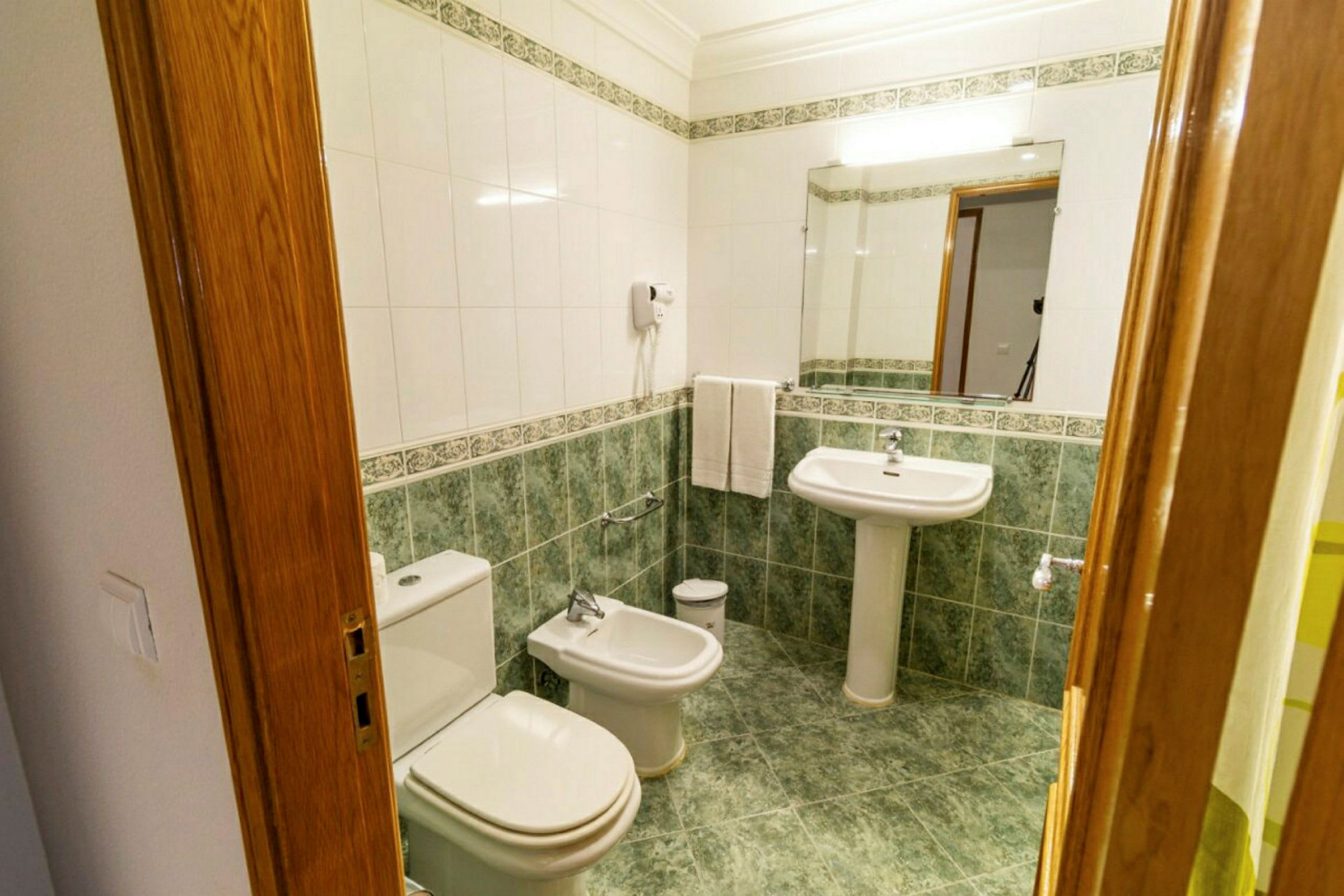 Et bad med toalett, bidet og servant. (AI-generert tekst)