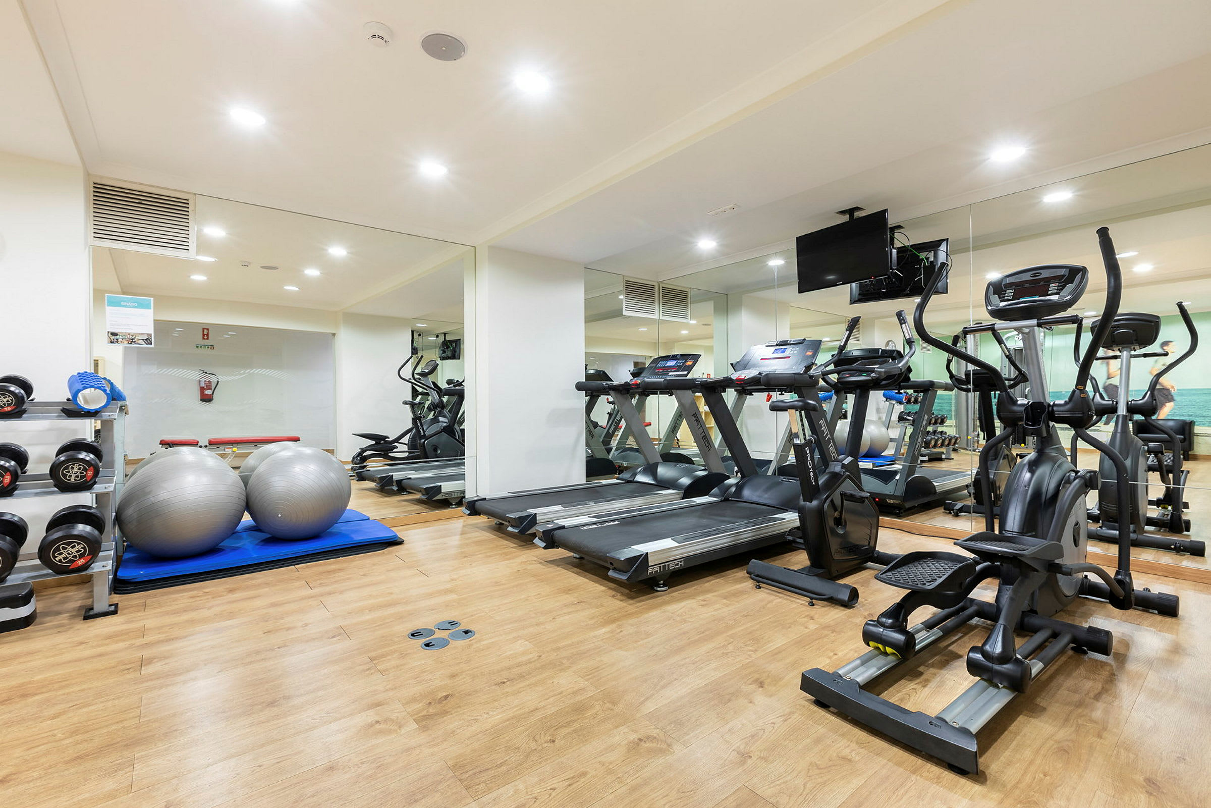 Et treningsstudio med treningsapparater, manualer og pilatesballer. (AI-generert tekst)