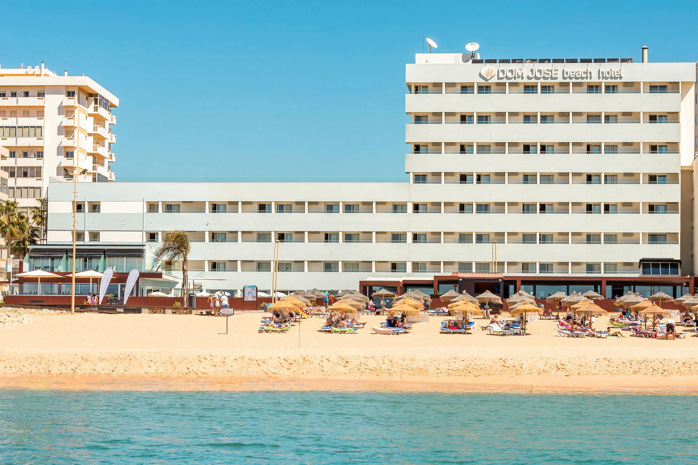 Hotell ved stranden med parasoller og solsenger. (AI-generert tekst)