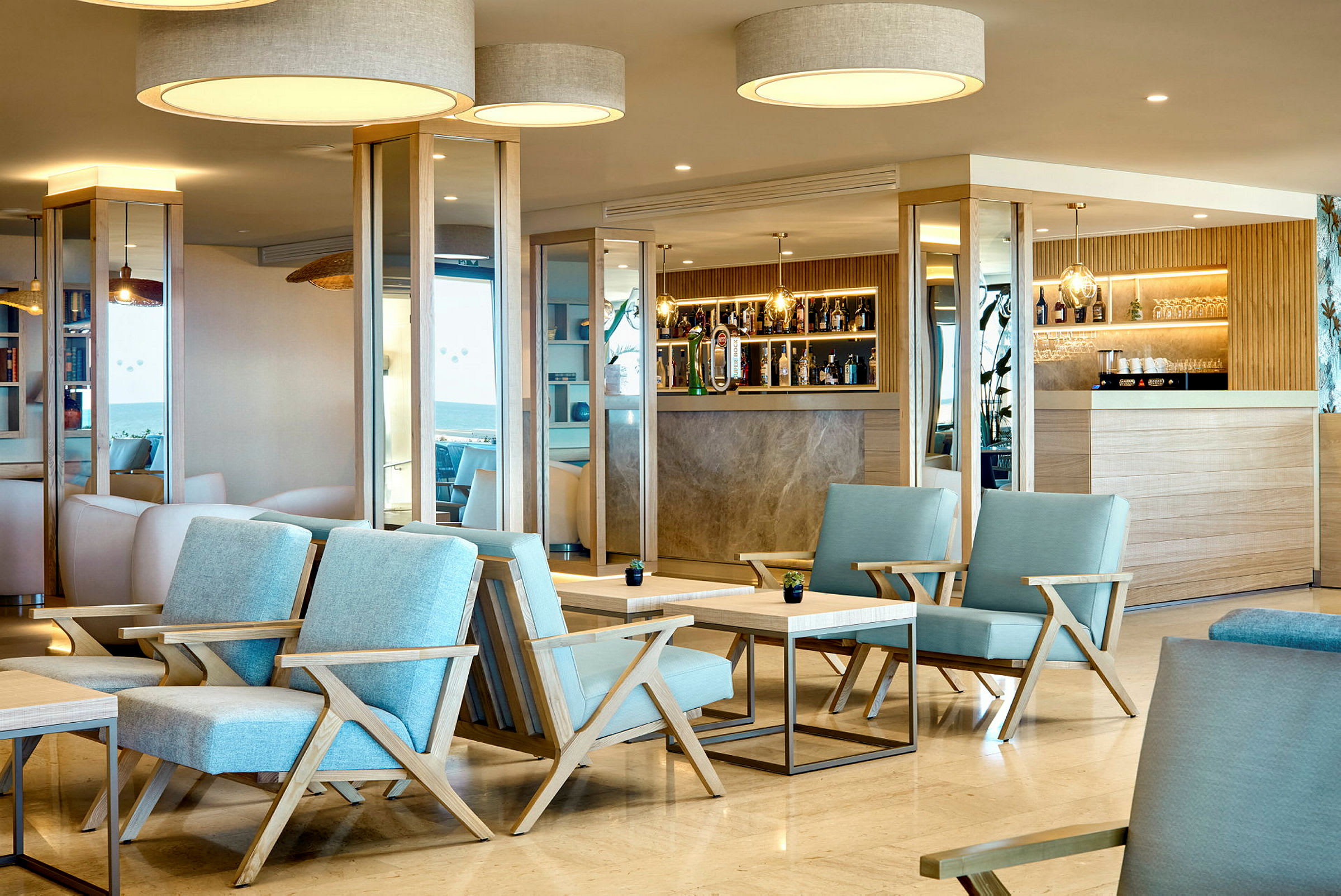 Et moderne hotellbarområde med blå stoler og tredetaljer. (AI-generert tekst)