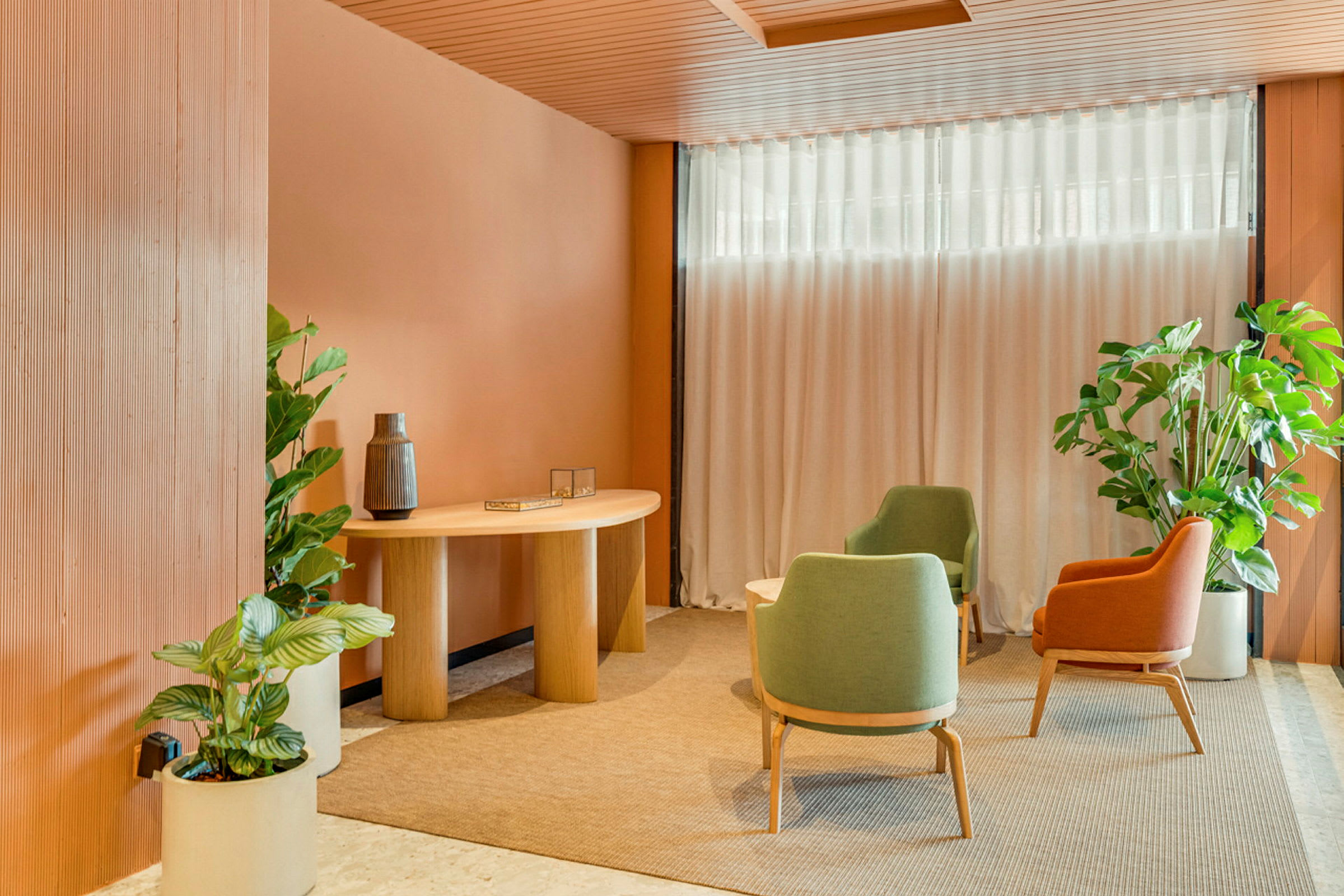 Et innbydende rom med moderne interiør, utstyrt med fargerike lenestoler, et trebord og omgitt av dekorative planter. (AI-generert tekst)
