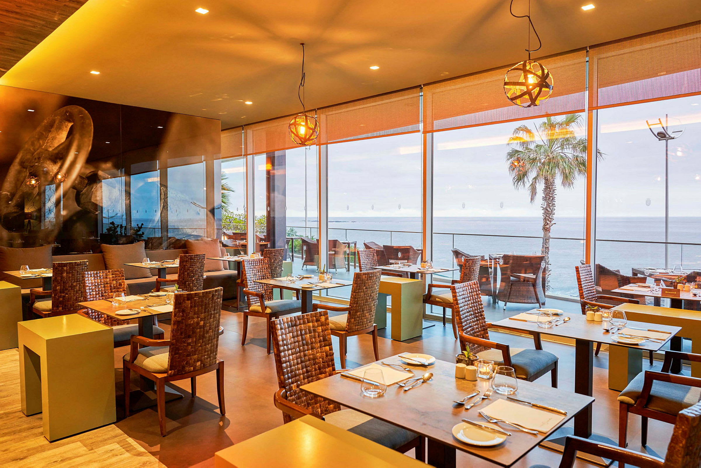 Restaurant med sitteplasser og store vinduer mot havet. (AI-generert tekst)