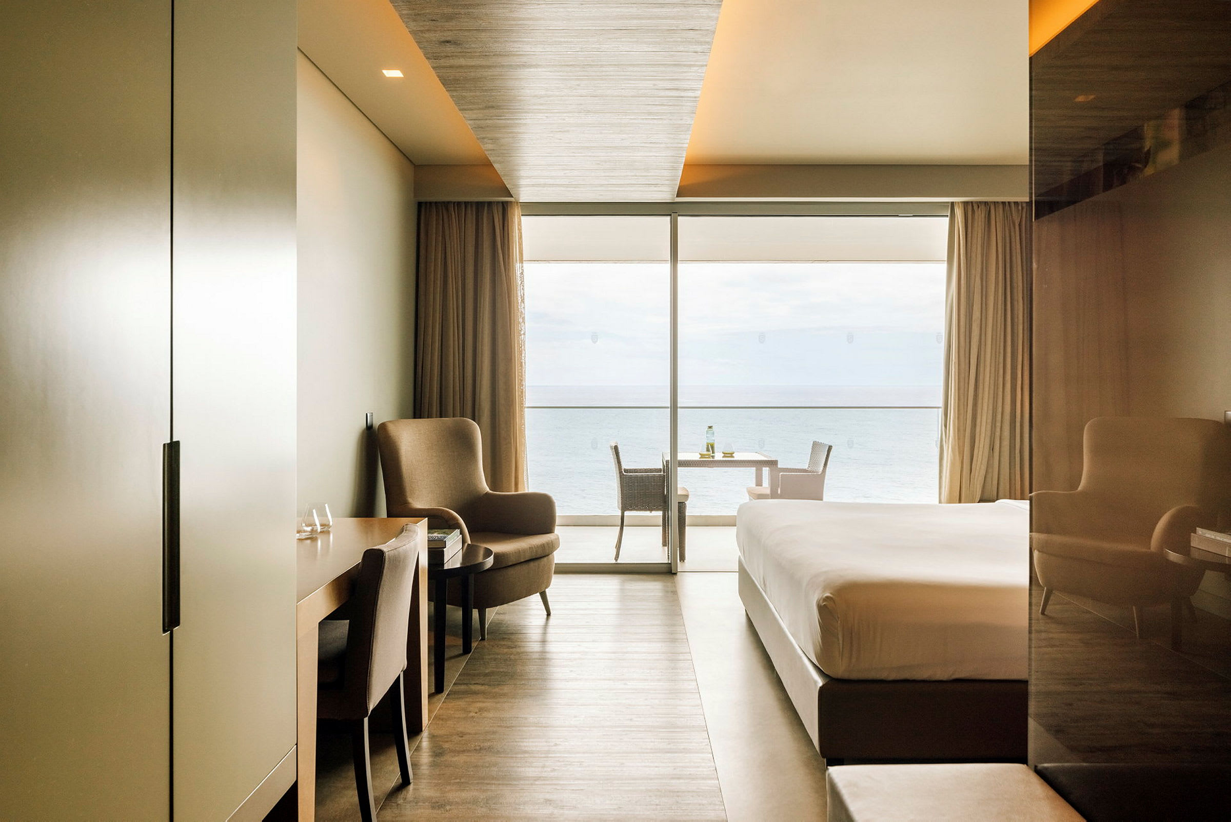 Moderne hotellrom med havutsikt gjennom store vinduer. (AI-generert tekst)
