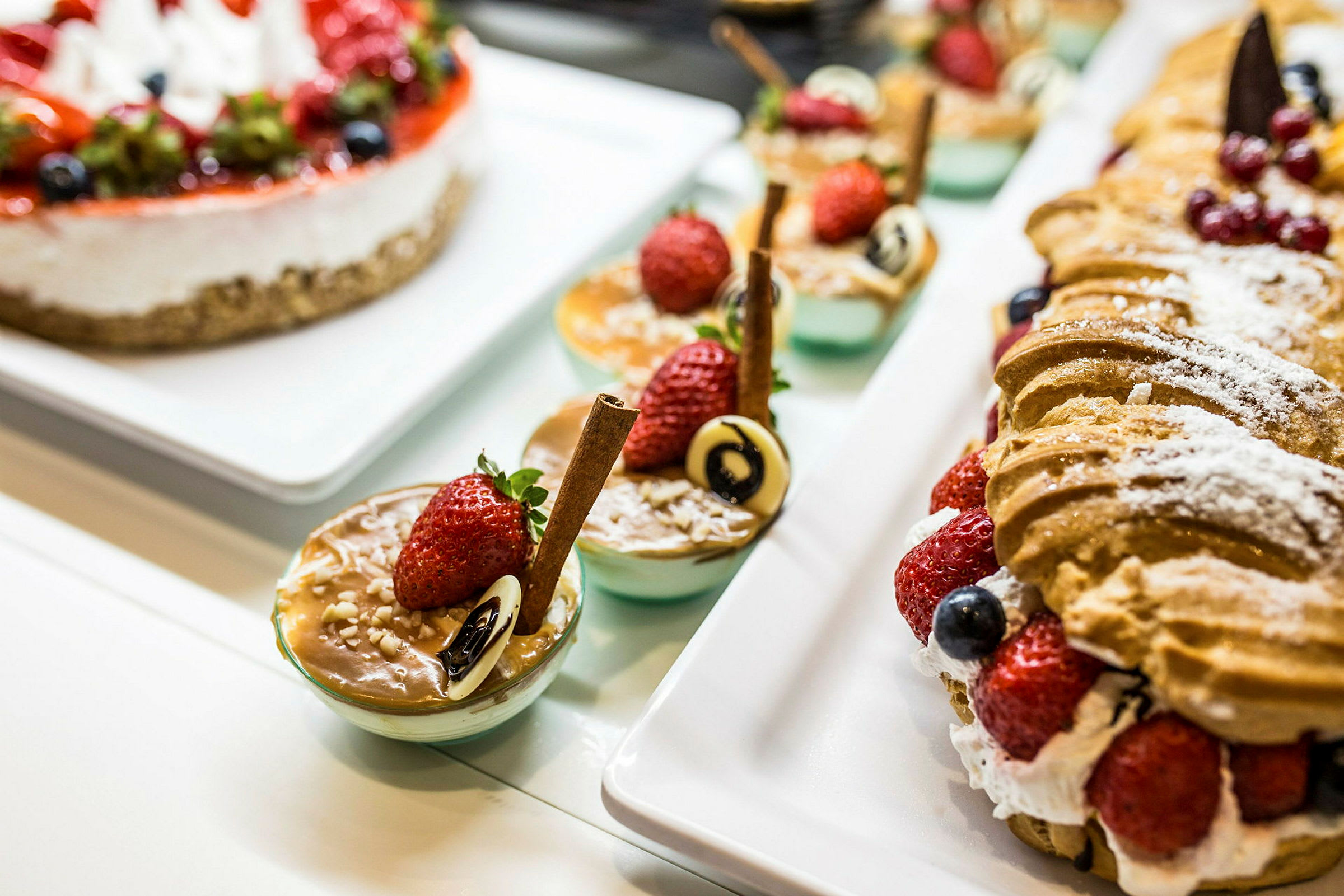 Et utvalg av desserter, inkludert bakverk og små serveringer med dekorasjoner som jordbær og sjokolade. (AI-generert tekst)