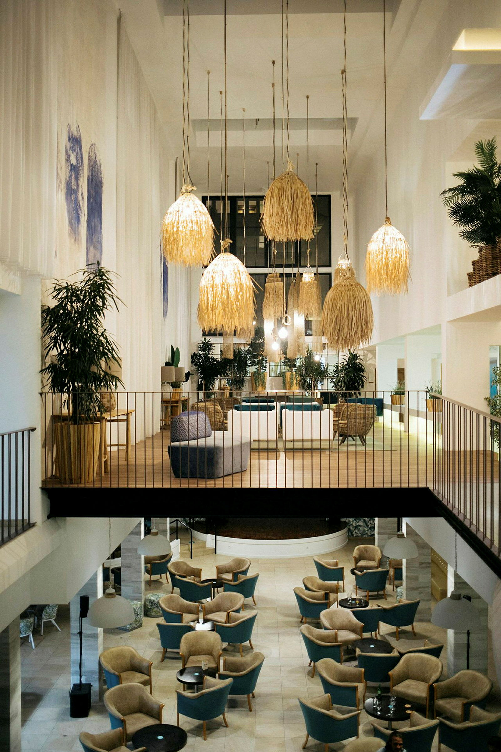 Interiøret av et romslig og elegant hotellområde med sittegrupper og store hengende lamper. (AI-generert tekst)