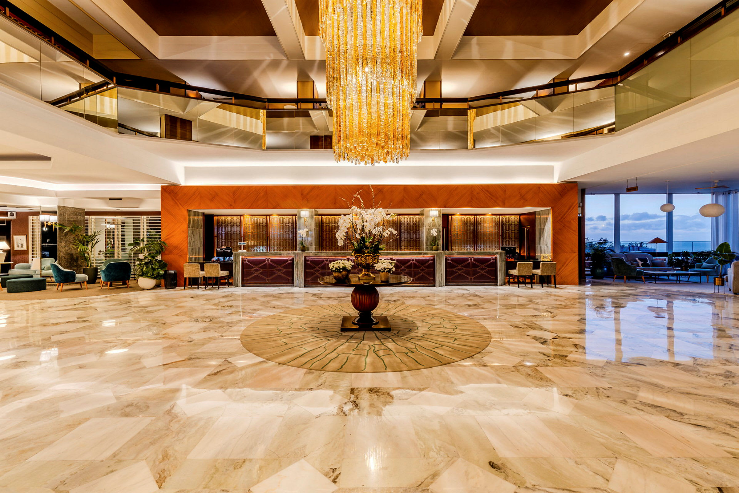 En elegant hotellobby med marmorgulv, en stor krystallysekrone og et resepsjonsområde. (AI-generert tekst)