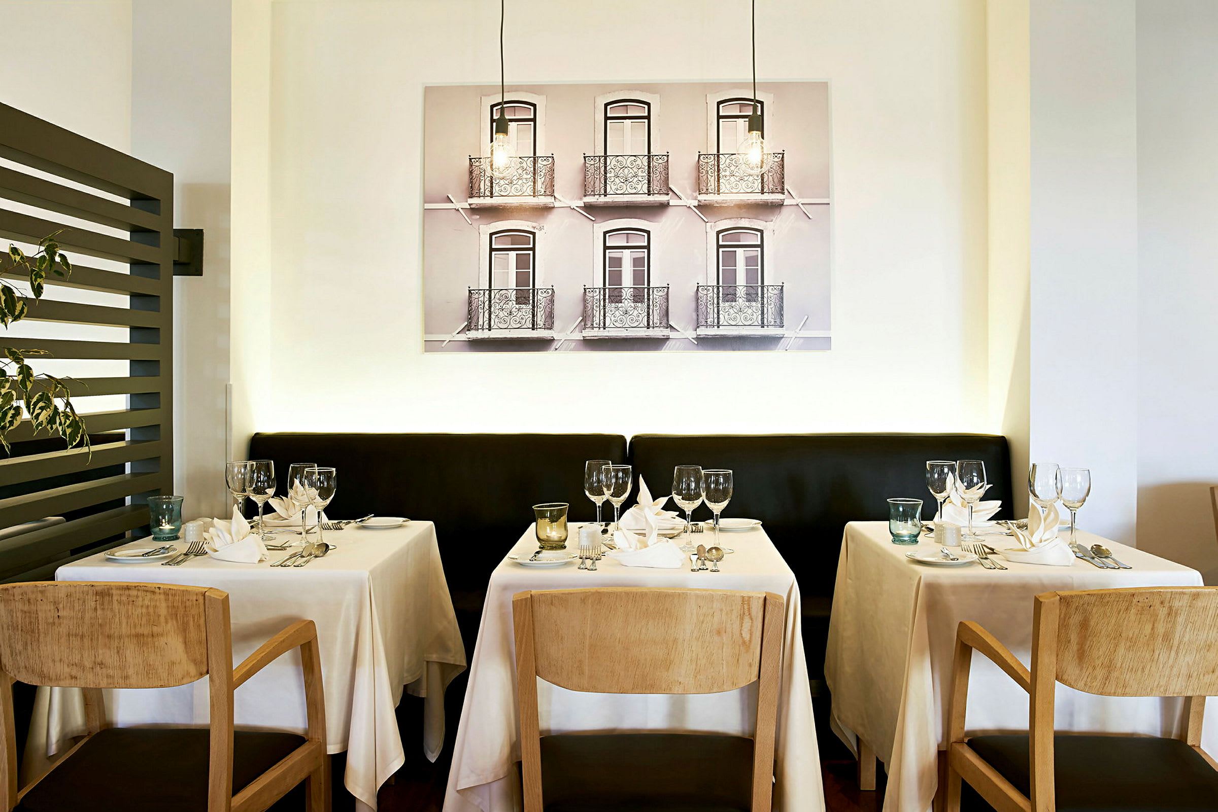 Restaurant med dekkede bord foran en vegg med fotokunst. (AI-generert tekst)