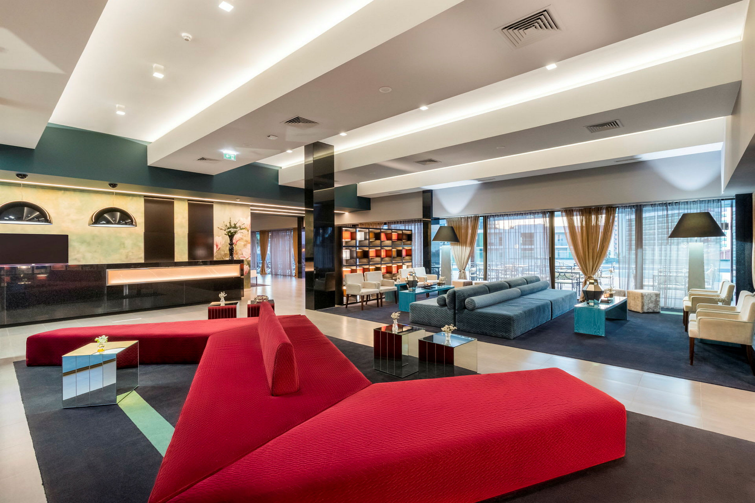 Moderne hotellobby med røde og blå møbler. (AI-generert tekst)