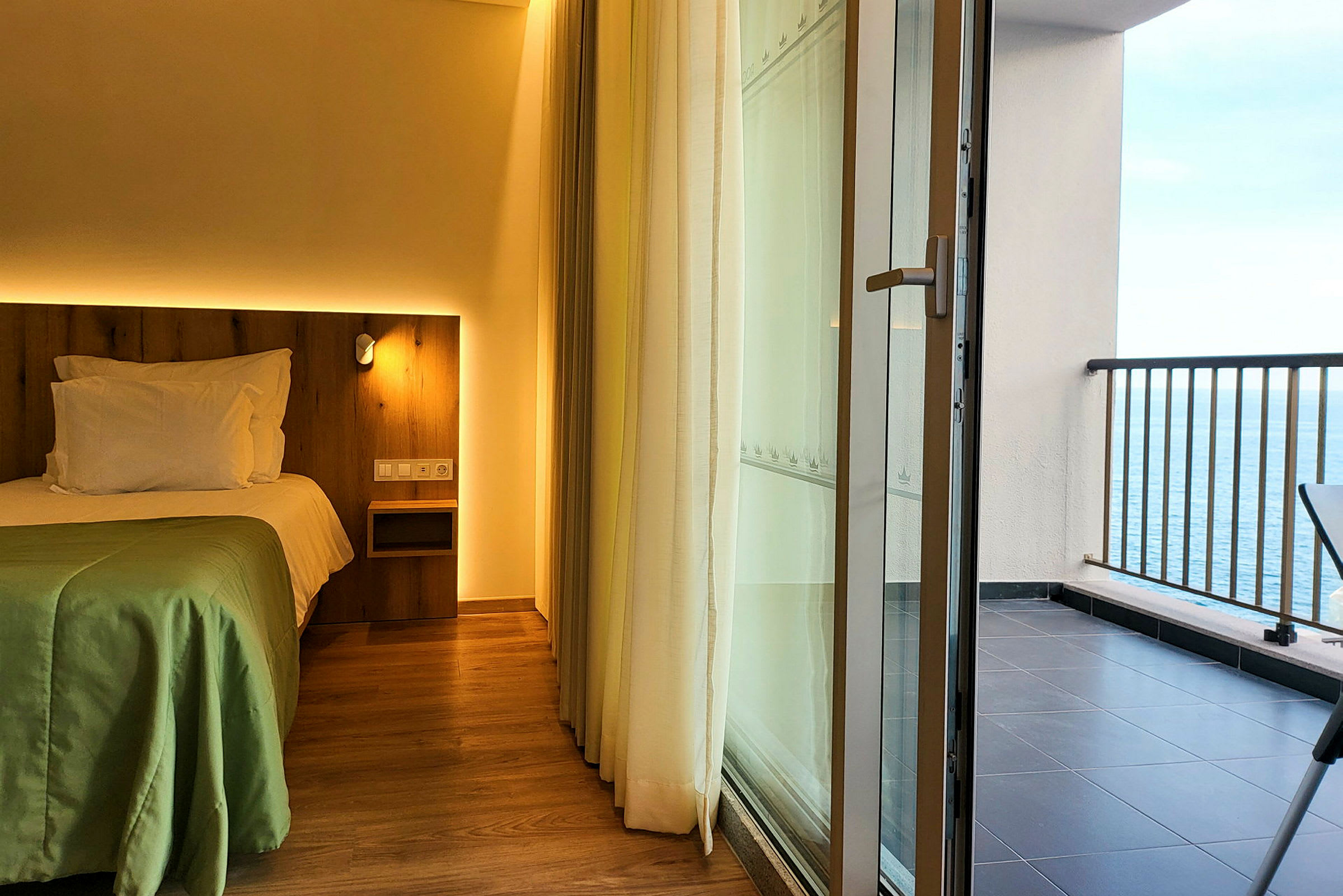 Hotellrom med seng og en balkong med utsikt over havet. (AI-generert tekst)