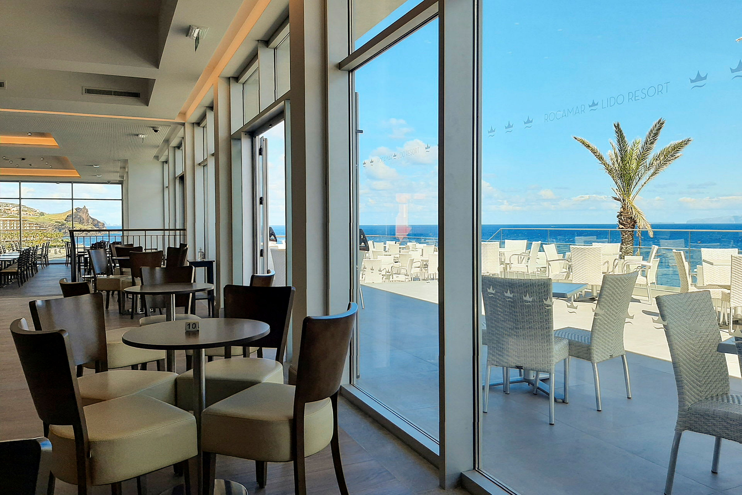 Bilde av en restaurant med sitteplasser inne og terrasse med utsikt over havet. (AI-generert tekst)