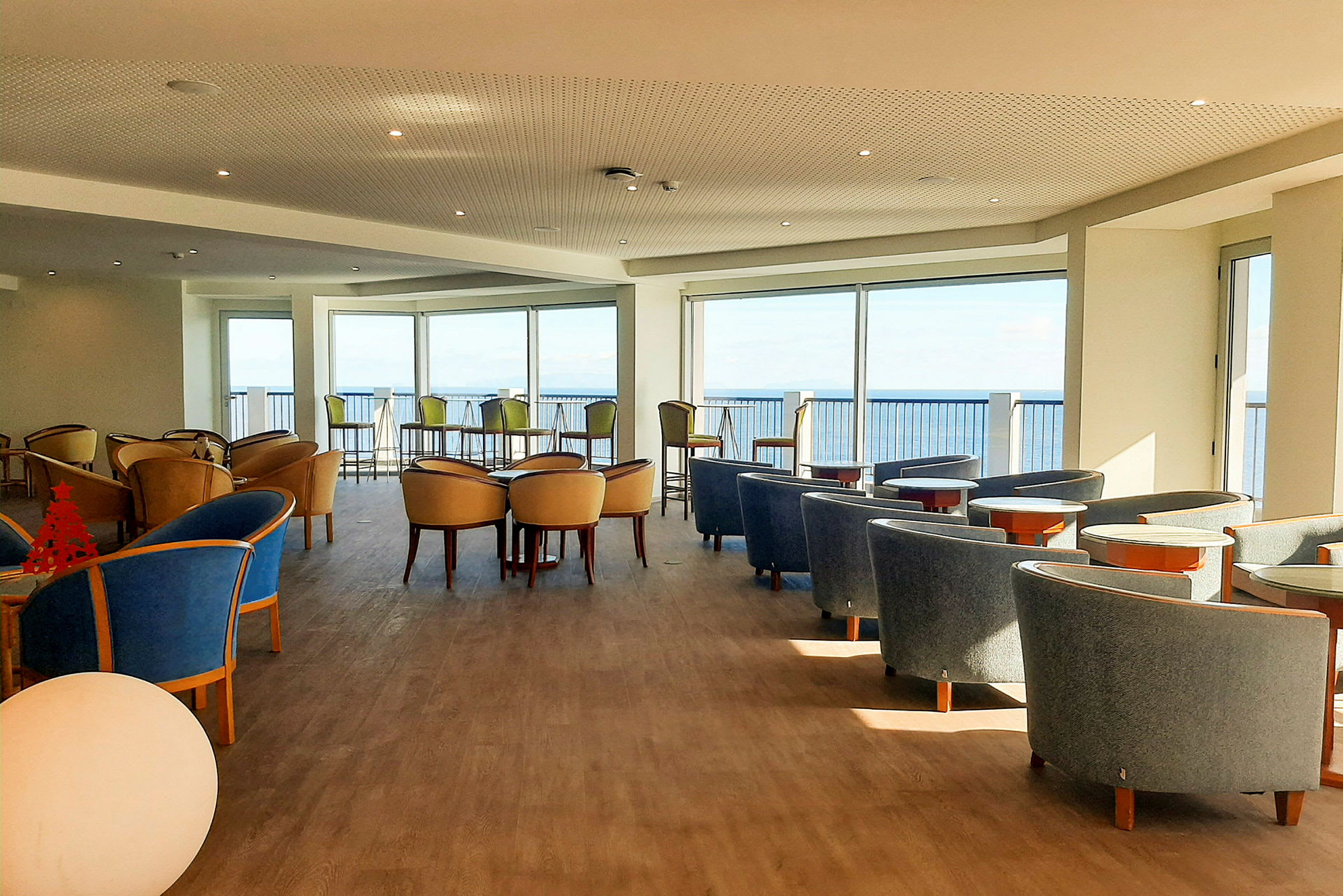 Et interiørbilde av en lys sittegruppe med utsikt mot havet. (AI-generert tekst)