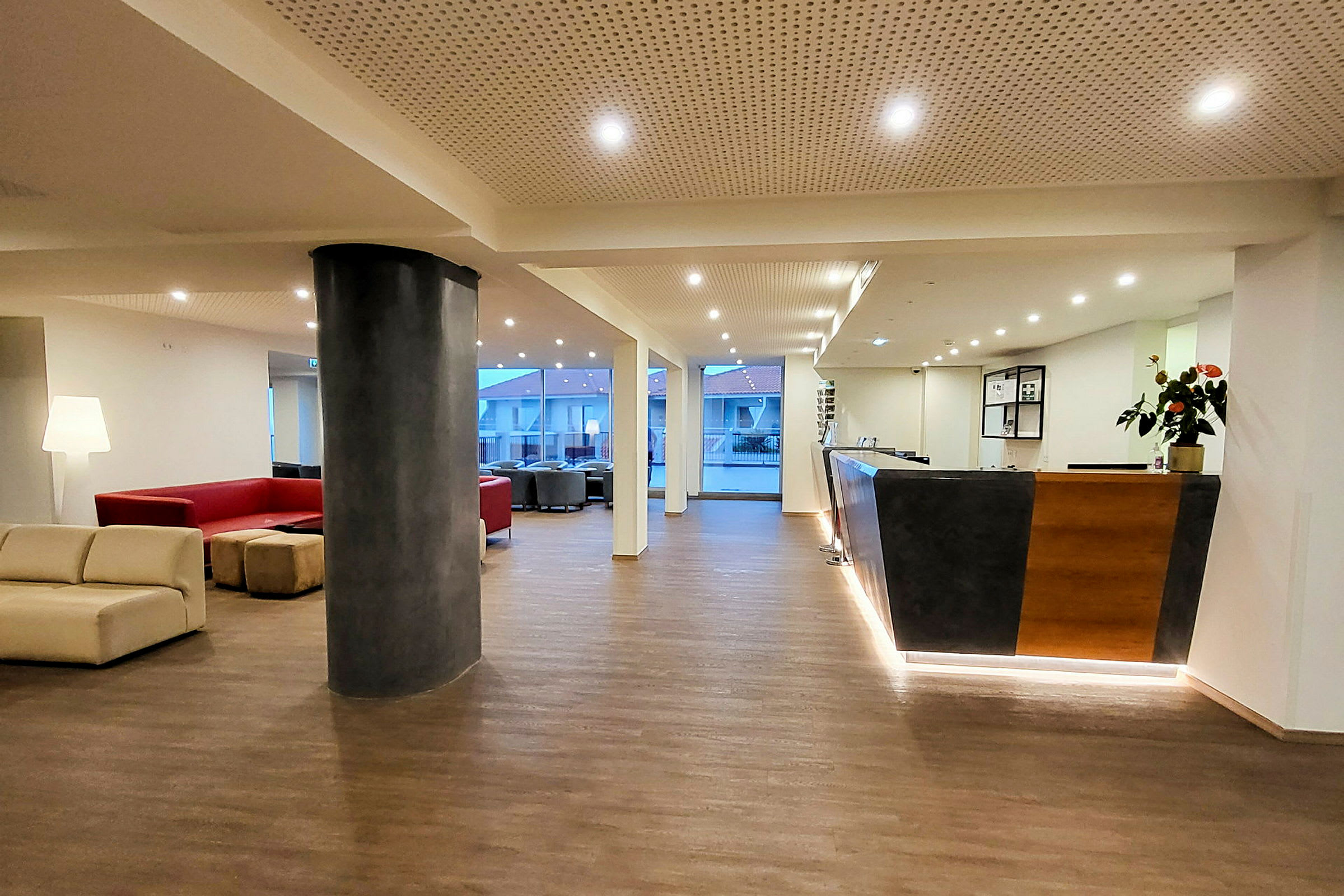 Hotellobby med sittegrupper, resepsjon og store vinduer. (AI-generert tekst)