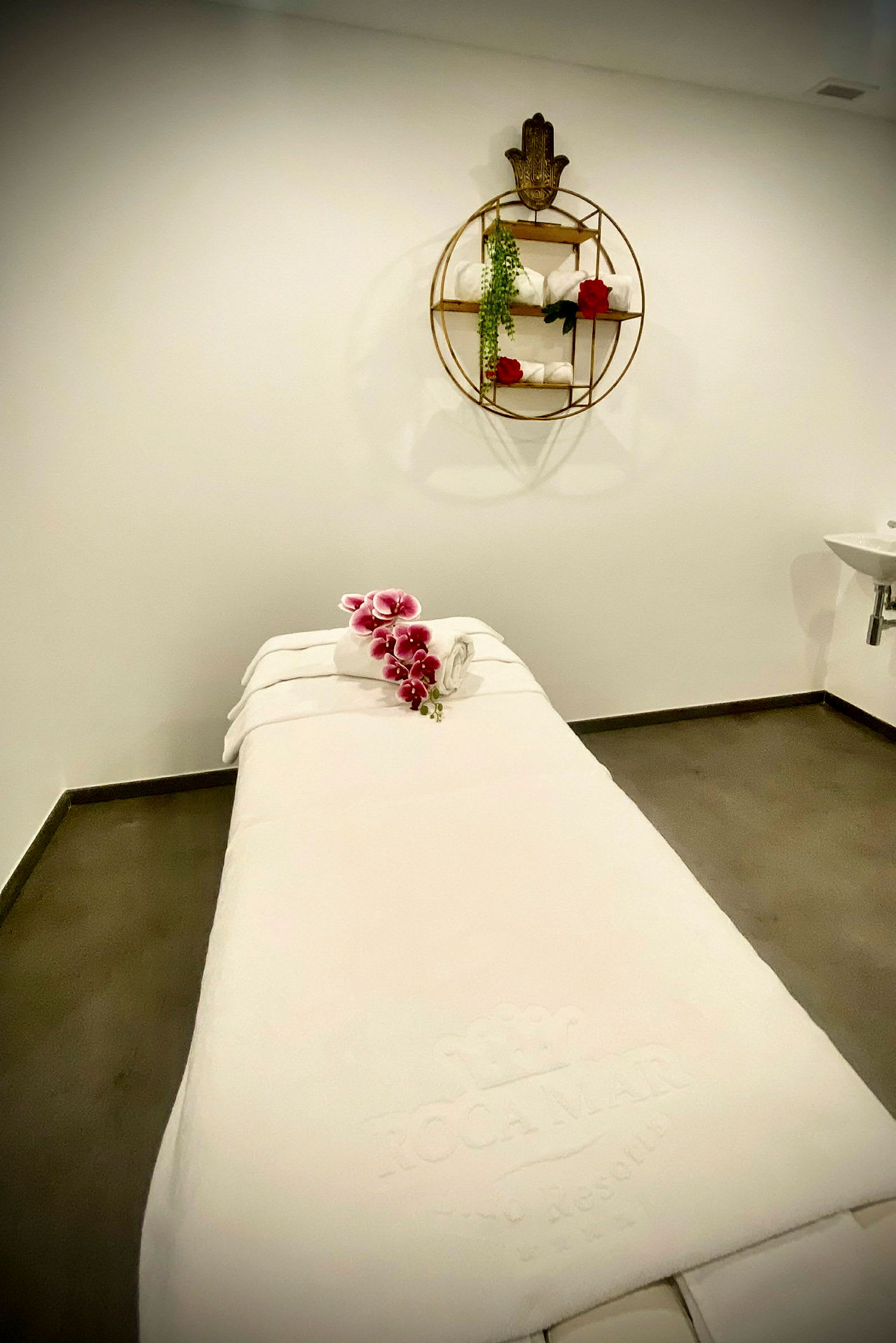 En massasjebenk i et spa-rom med håndklær og blomster. (AI-generert tekst)