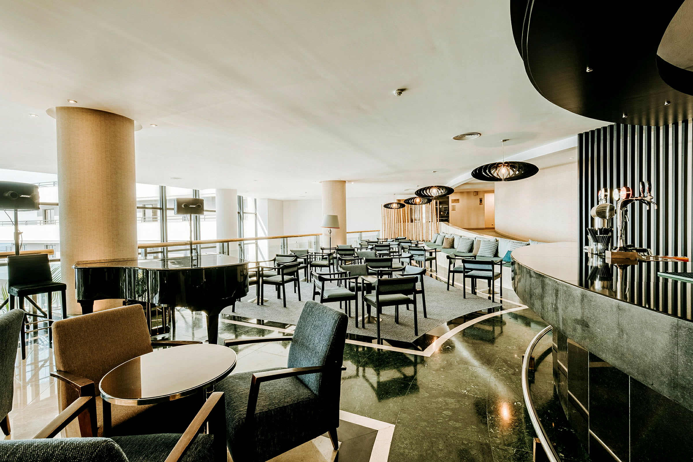 En moderne hotellobby med sittegrupper og et svart flygel. (AI-generert tekst)