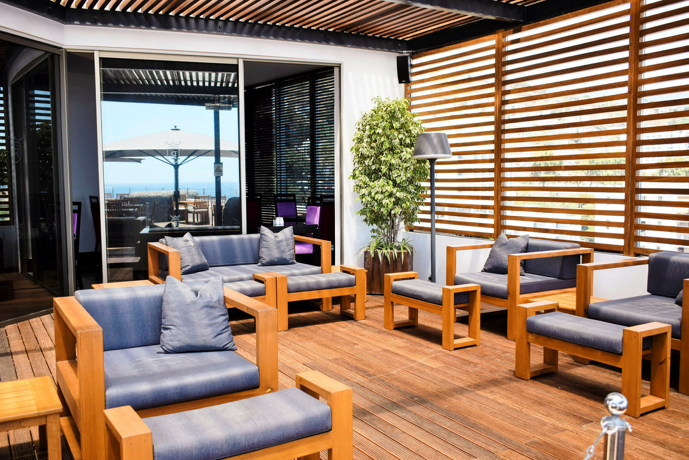Terrasse med moderne tre- og tekstilmøbler, lamper og en potteplante. (AI-generert tekst)