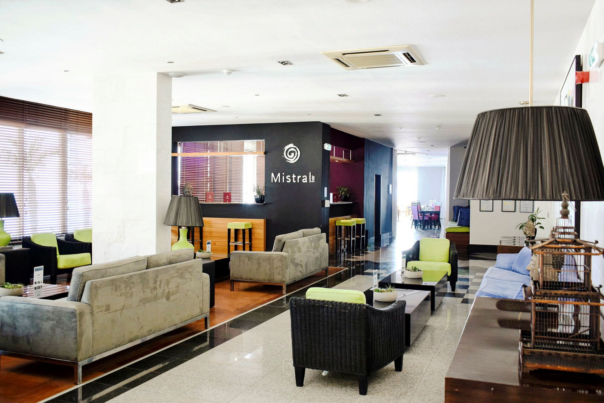 En hotellobby med sofaer, bord og en bar i bakgrunnen. (AI-generert tekst)