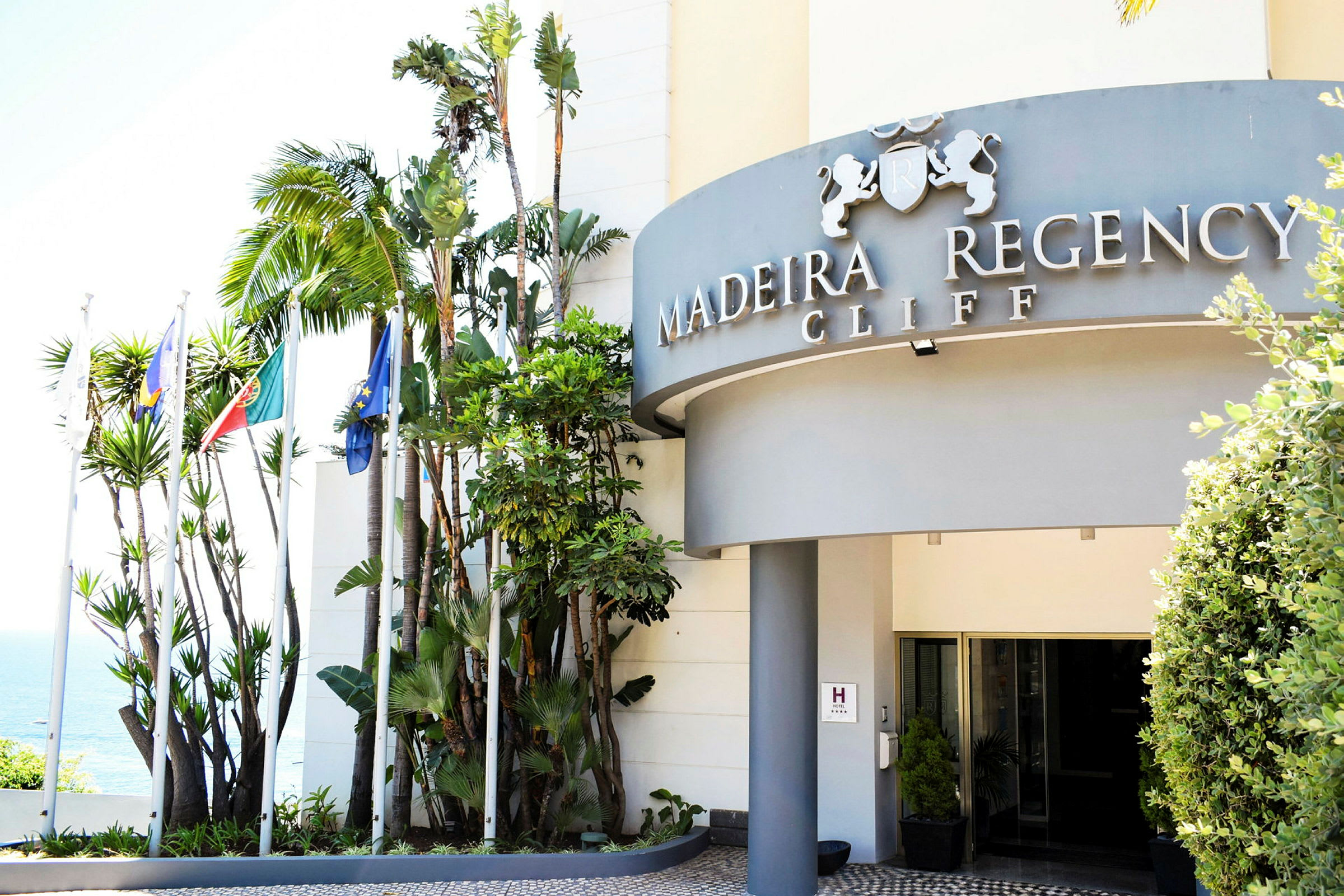Bygning med skilt som viser "Madeira Regency Cliff" og omgitt av palmer. (AI-generert tekst)