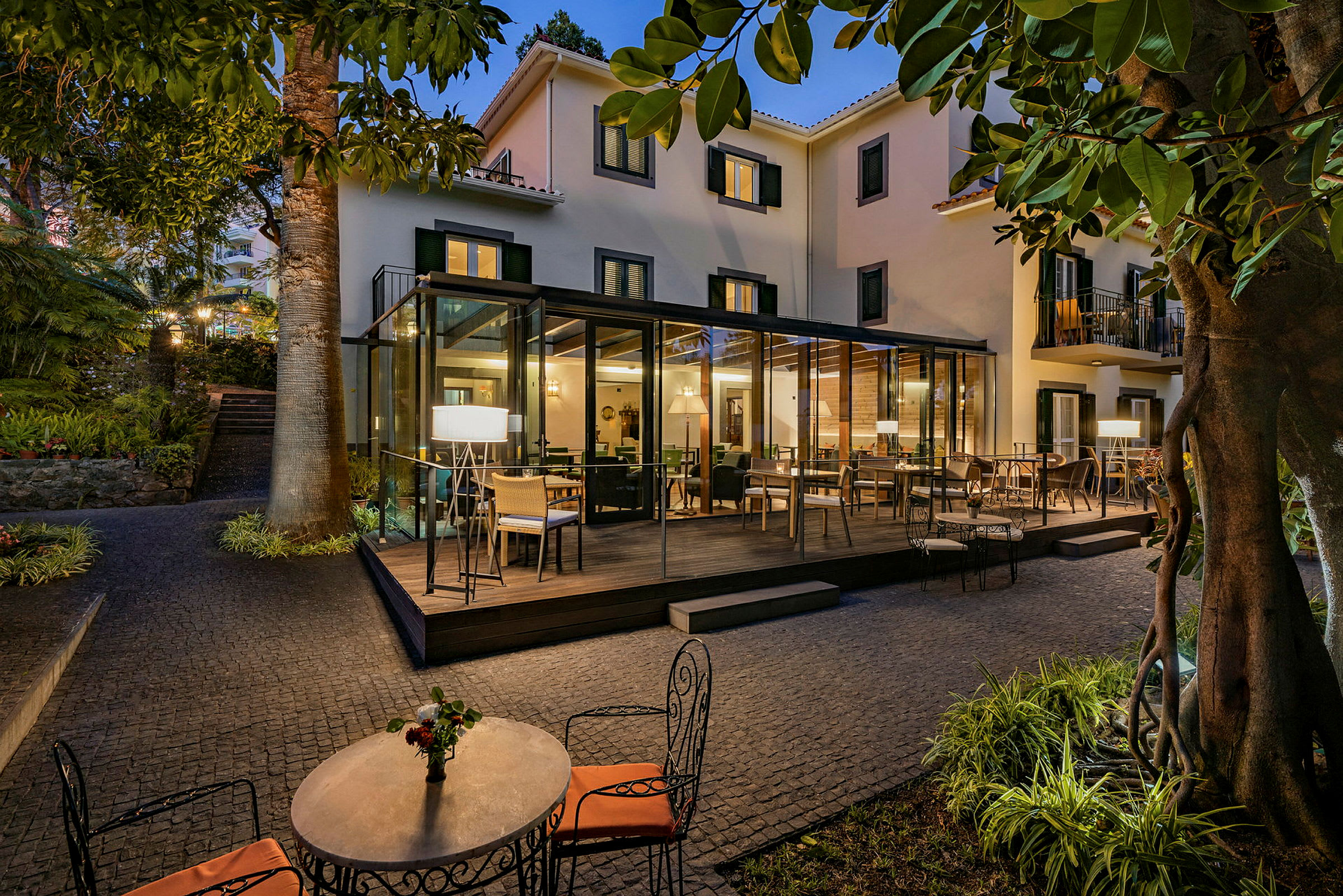 En terrasse med sitteplasser på et hotell, omgitt av grøntområder og belysning. (AI-generert tekst)