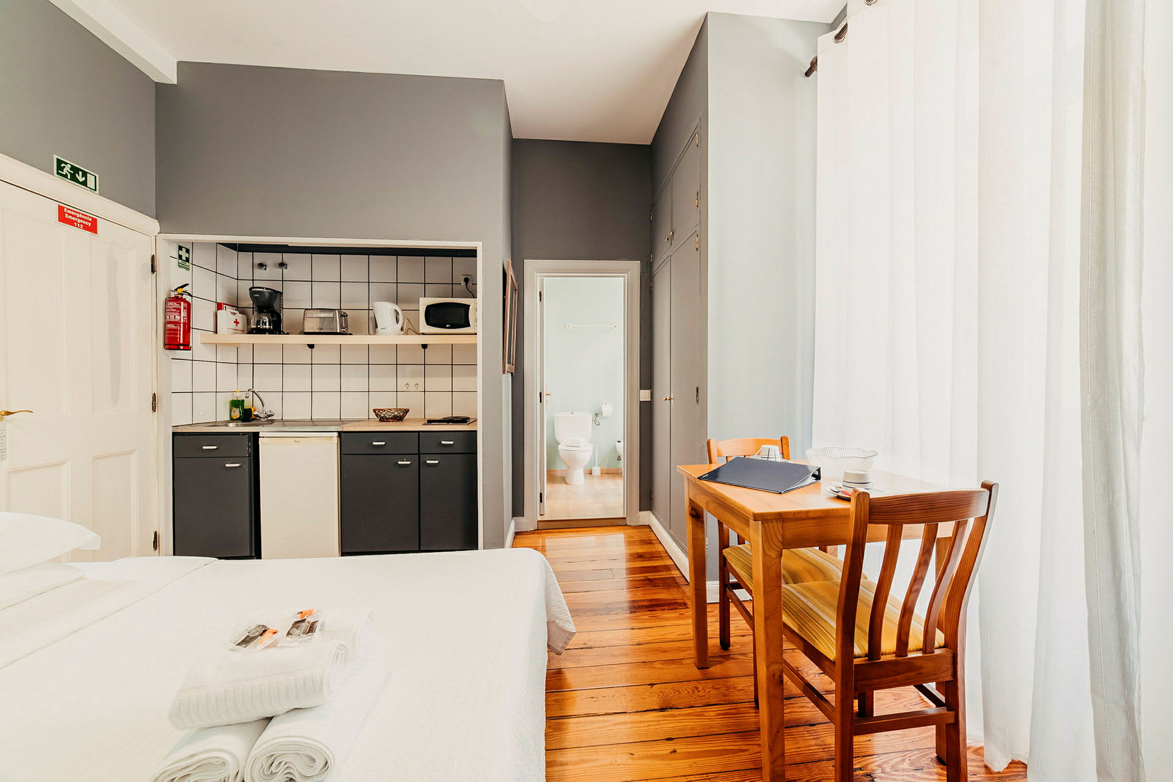 Et hotellrom med kjøkkenområde, spisebord og bad. (AI-generert tekst)