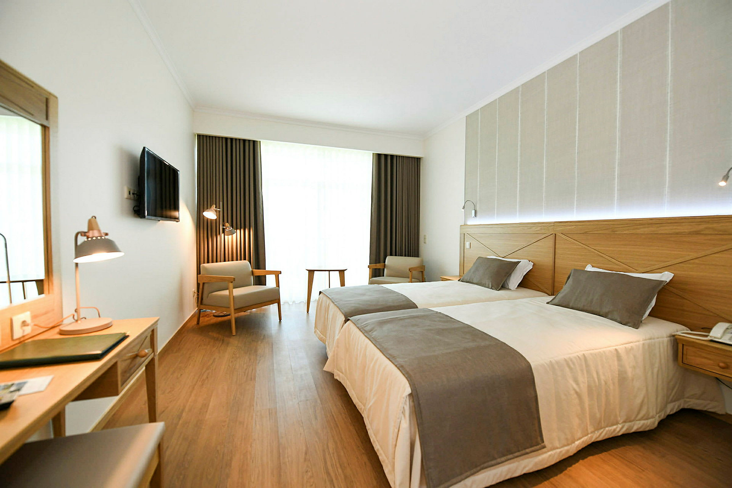 Hotellrom med to enkeltsenger, skrivebord og sitteplasser. (AI-generert tekst)