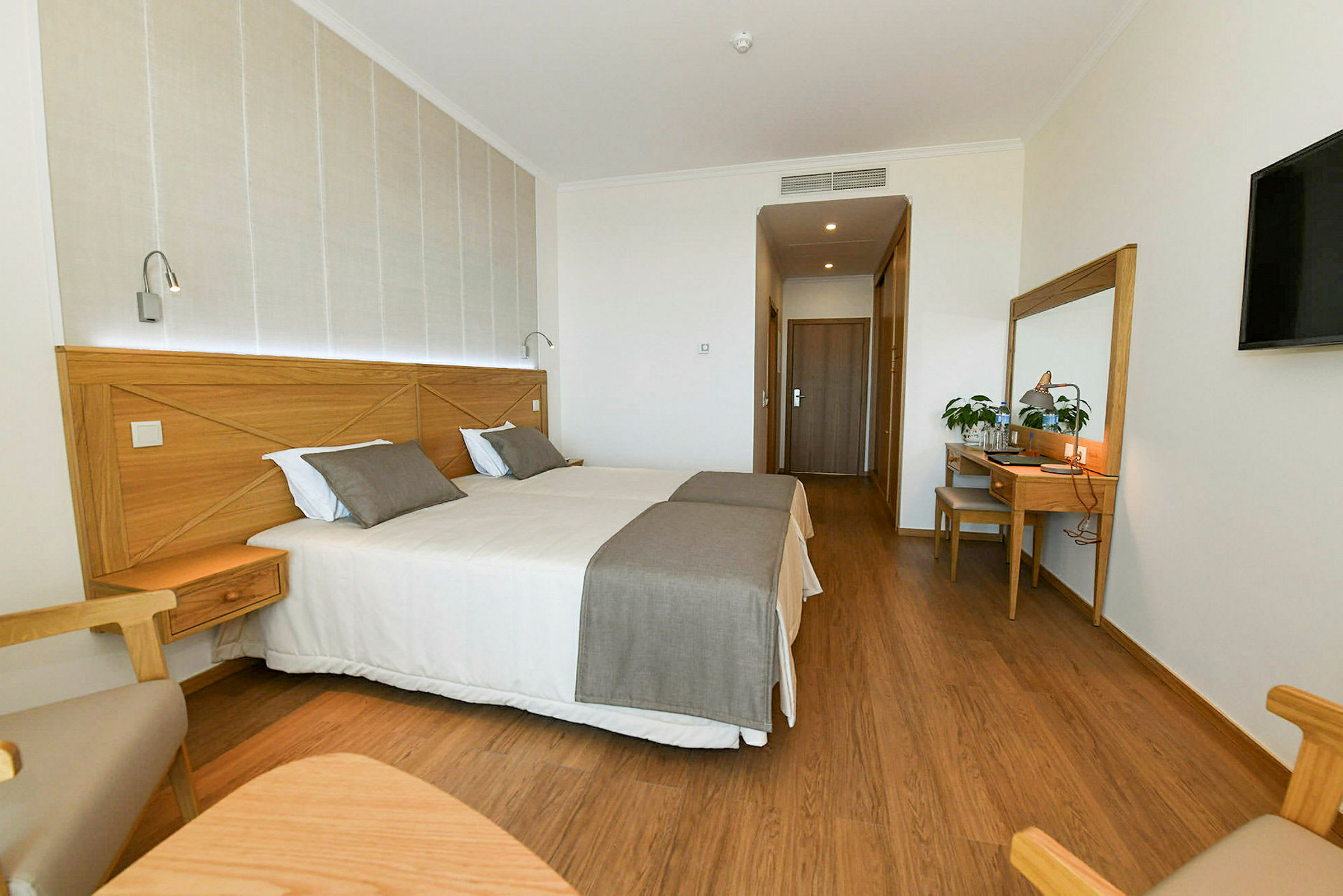 Moderne innredet hotellrom med to enkeltsenger og tremøbler. (AI-generert tekst)