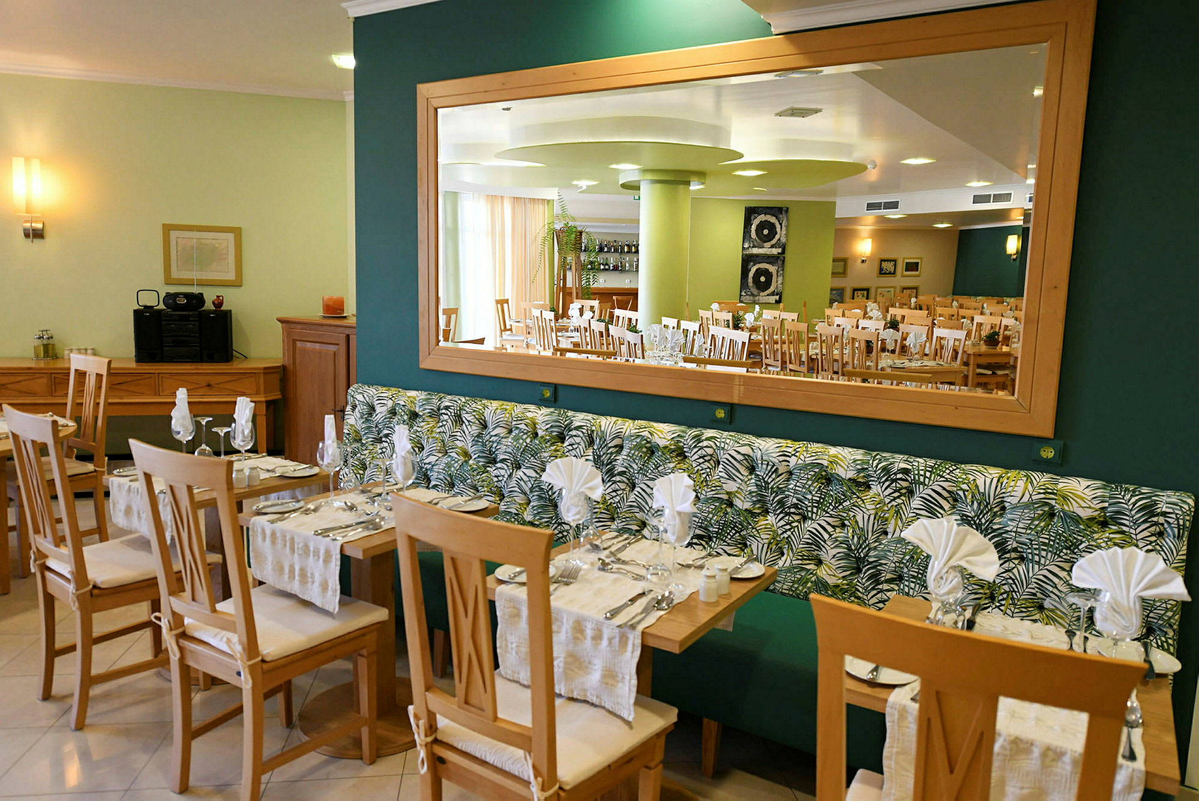 Restaurant med bord og stoler samt speil på veggen. (AI-generert tekst)