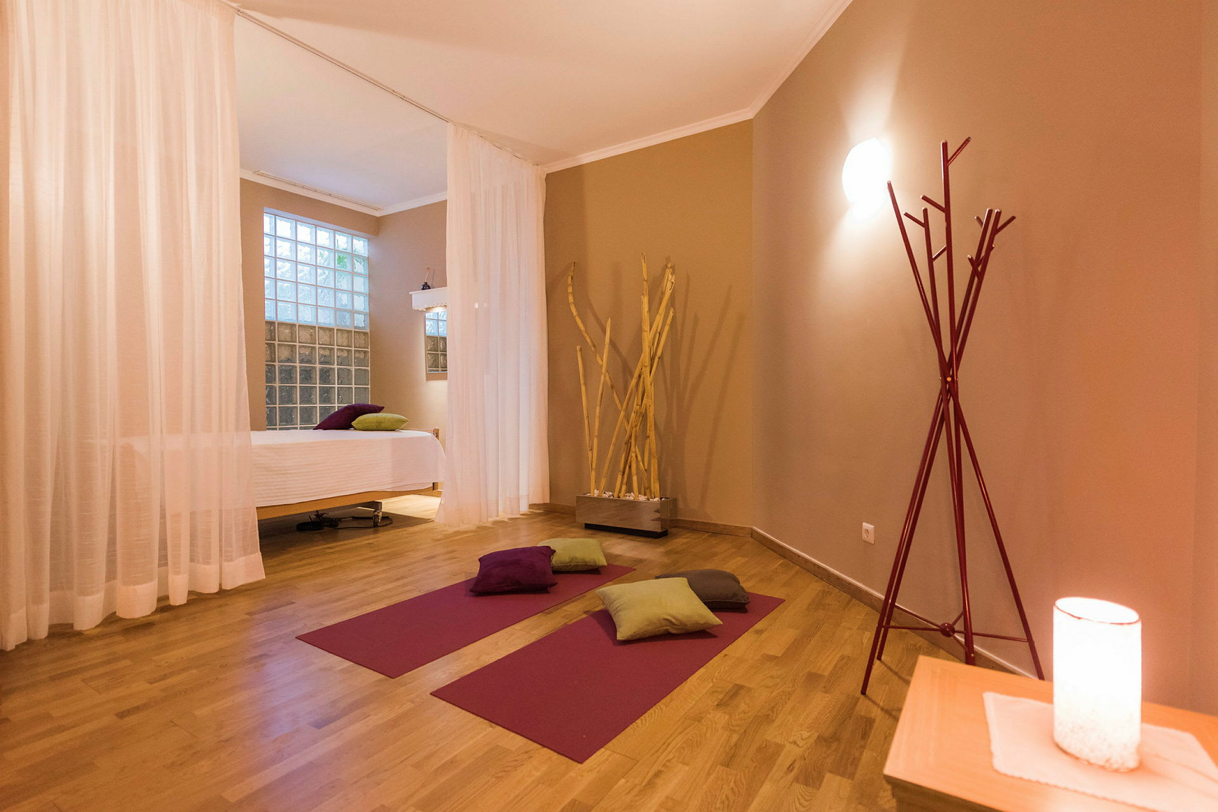 Et yogarom med matter, puter og en massasjebenk, innredet med varme fargetoner. (AI-generert tekst)