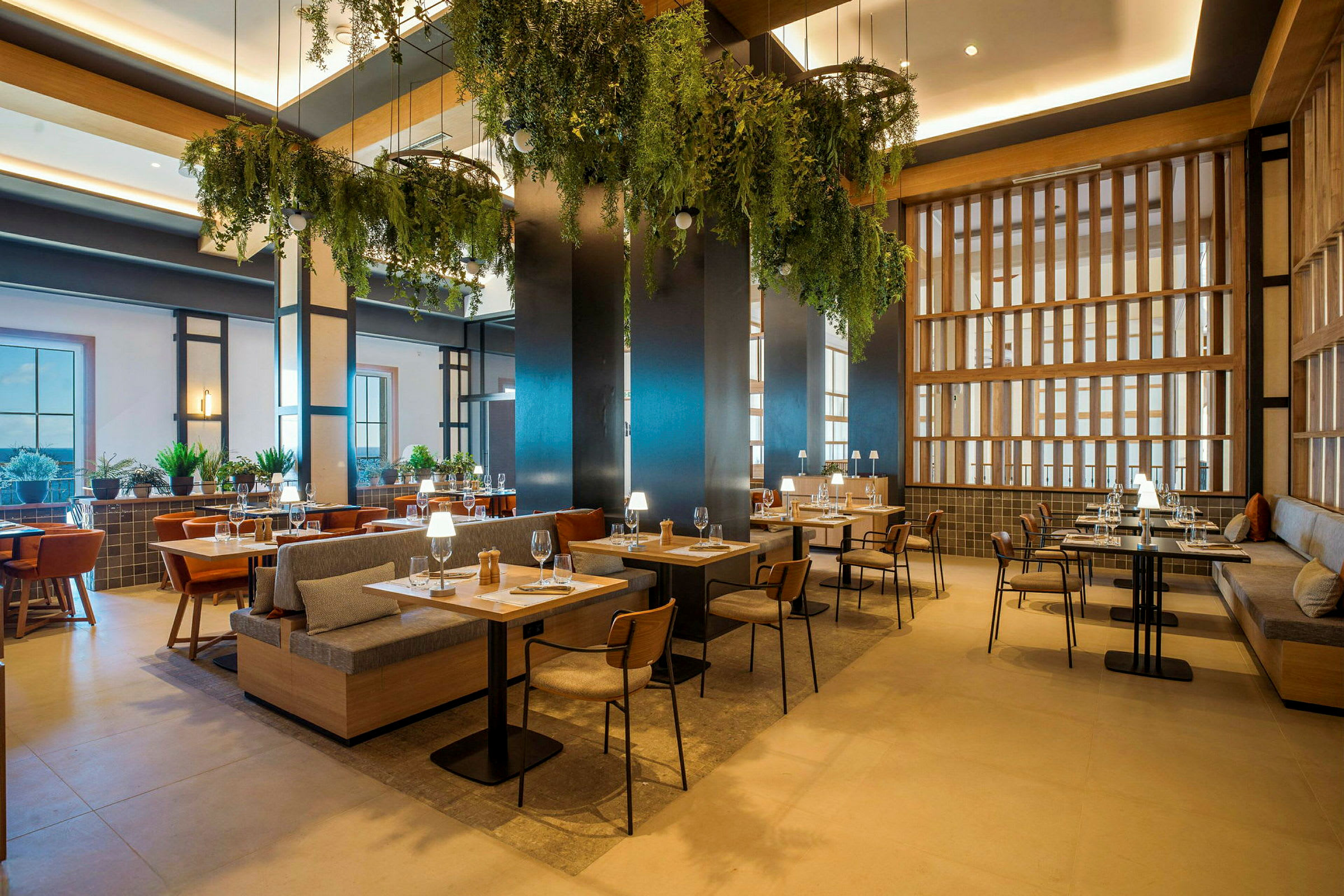 En moderne restaurant med tremøbler, grønne planteoppsatser og subtil belysning. (AI-generert tekst)