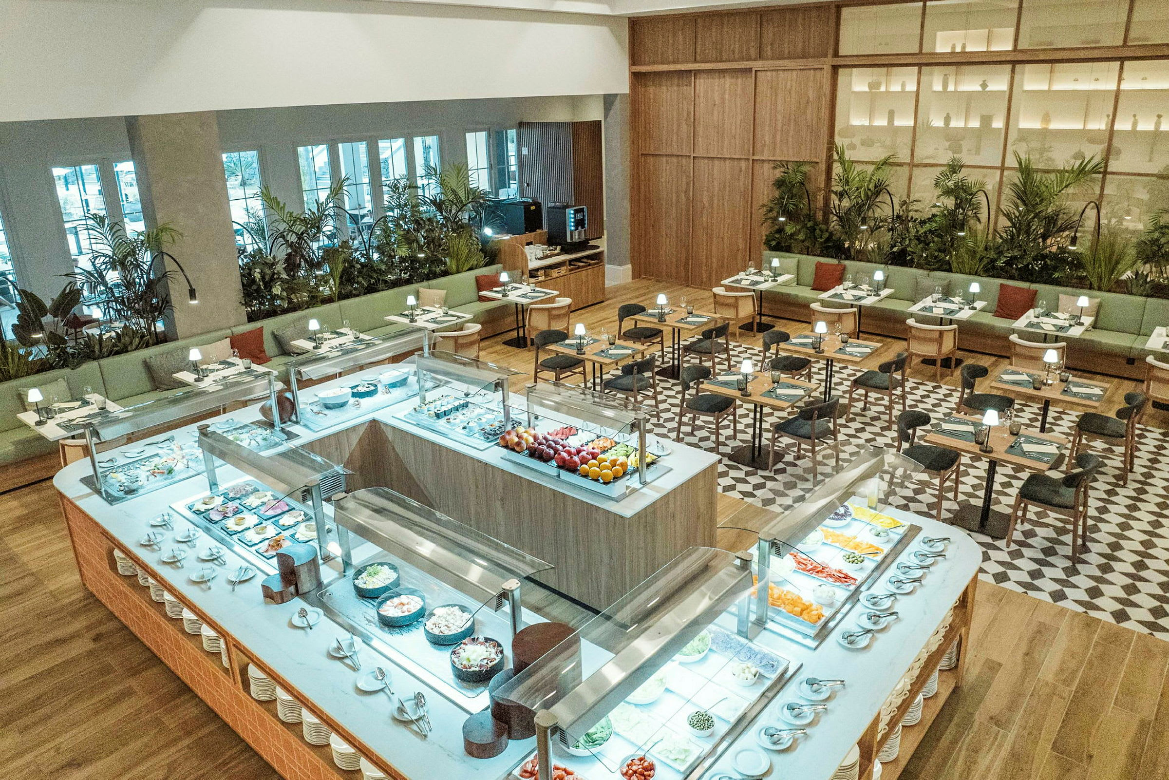 Et godt opplyst restaurantområde med buffetbord i forgrunnen fylt med forskjellige retter og sitteplasser i bakgrunnen. (AI-generert tekst)