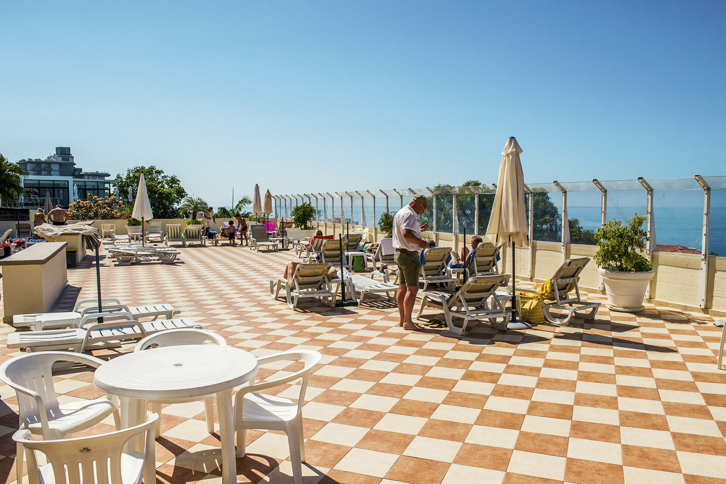 En solterrasse med solsenger og parasoller samt havutsikt. (AI-generert tekst)