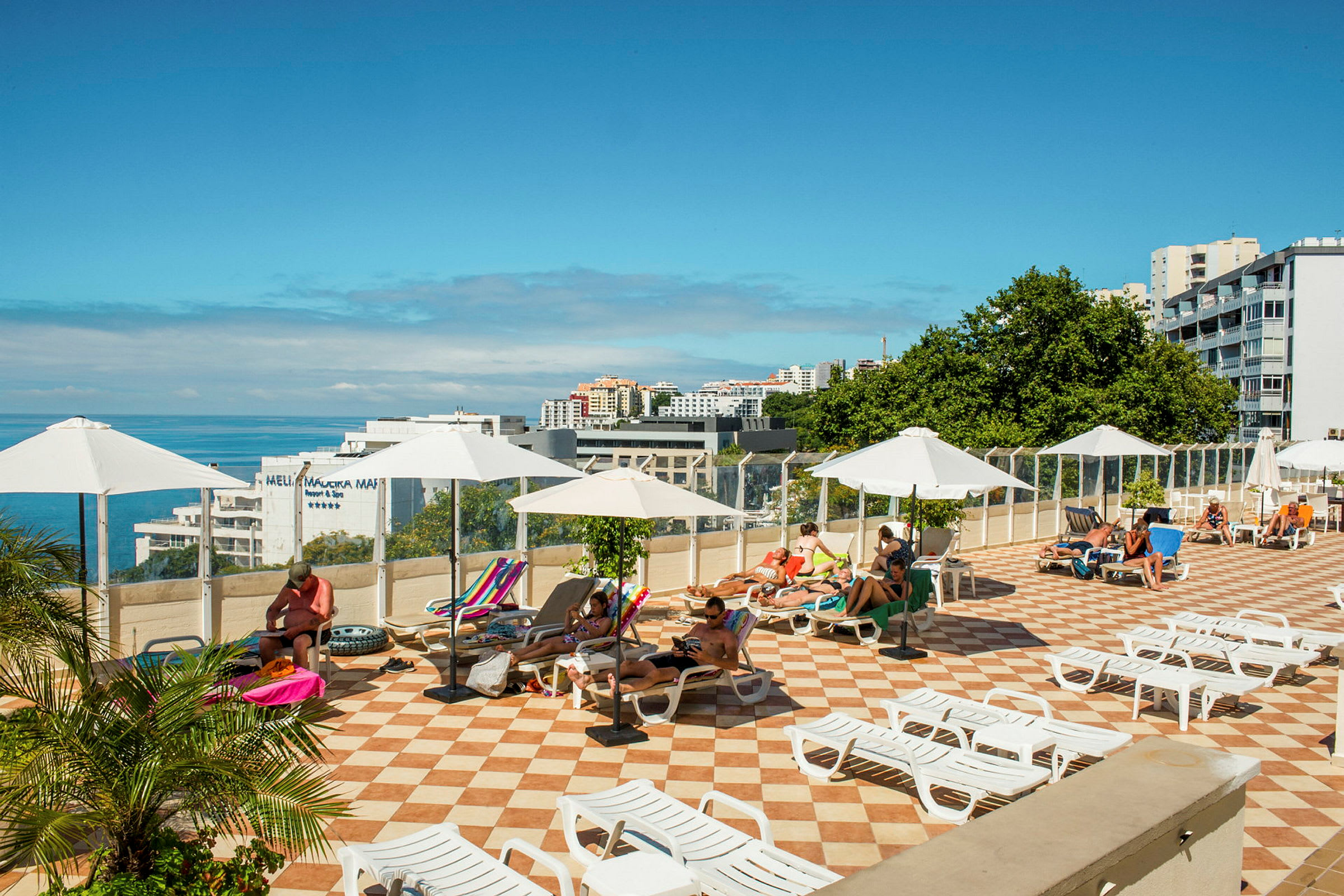 Solterrasse med solsenger og parasoller, med utsikt mot havet. (AI-generert tekst)
