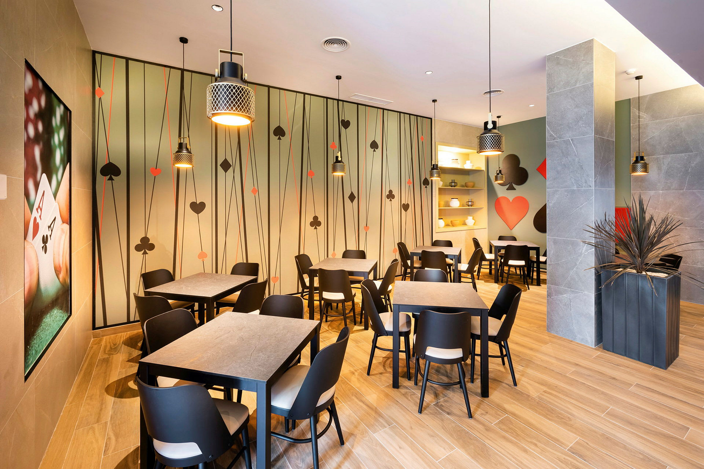 Bilde av en restaurantinnredning med spillekorttema, sittegrupper og veggdekorasjoner. (AI-generert tekst)