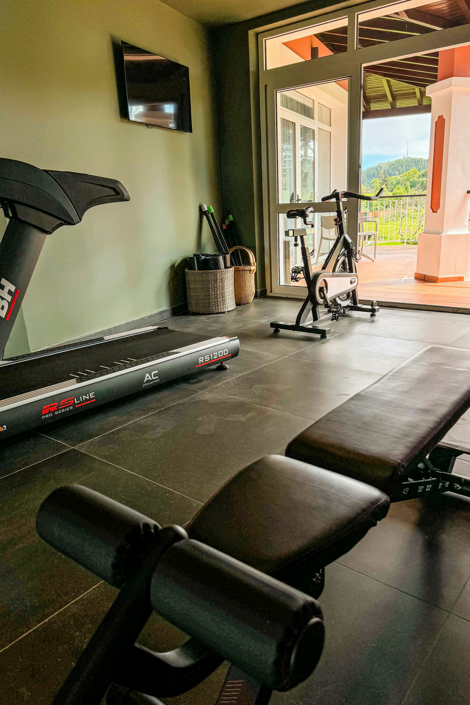 Et hjemmegym med treningsutstyr, inkludert et løpebånd, en treningssykkel og en benk. (AI-generert tekst)