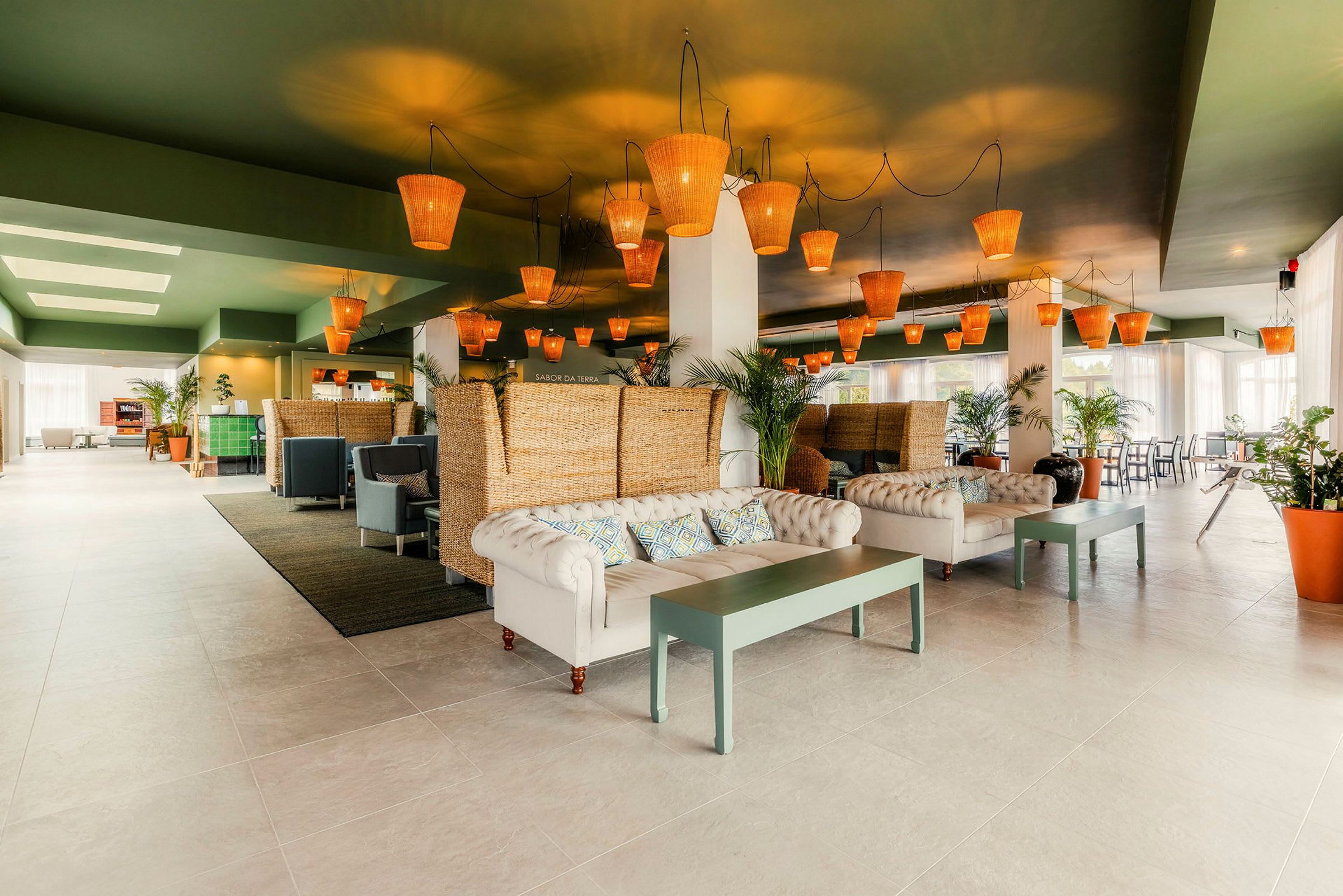 En moderne og elegant lobby med sofaer, bord og rottinglamper i taket. (AI-generert tekst)