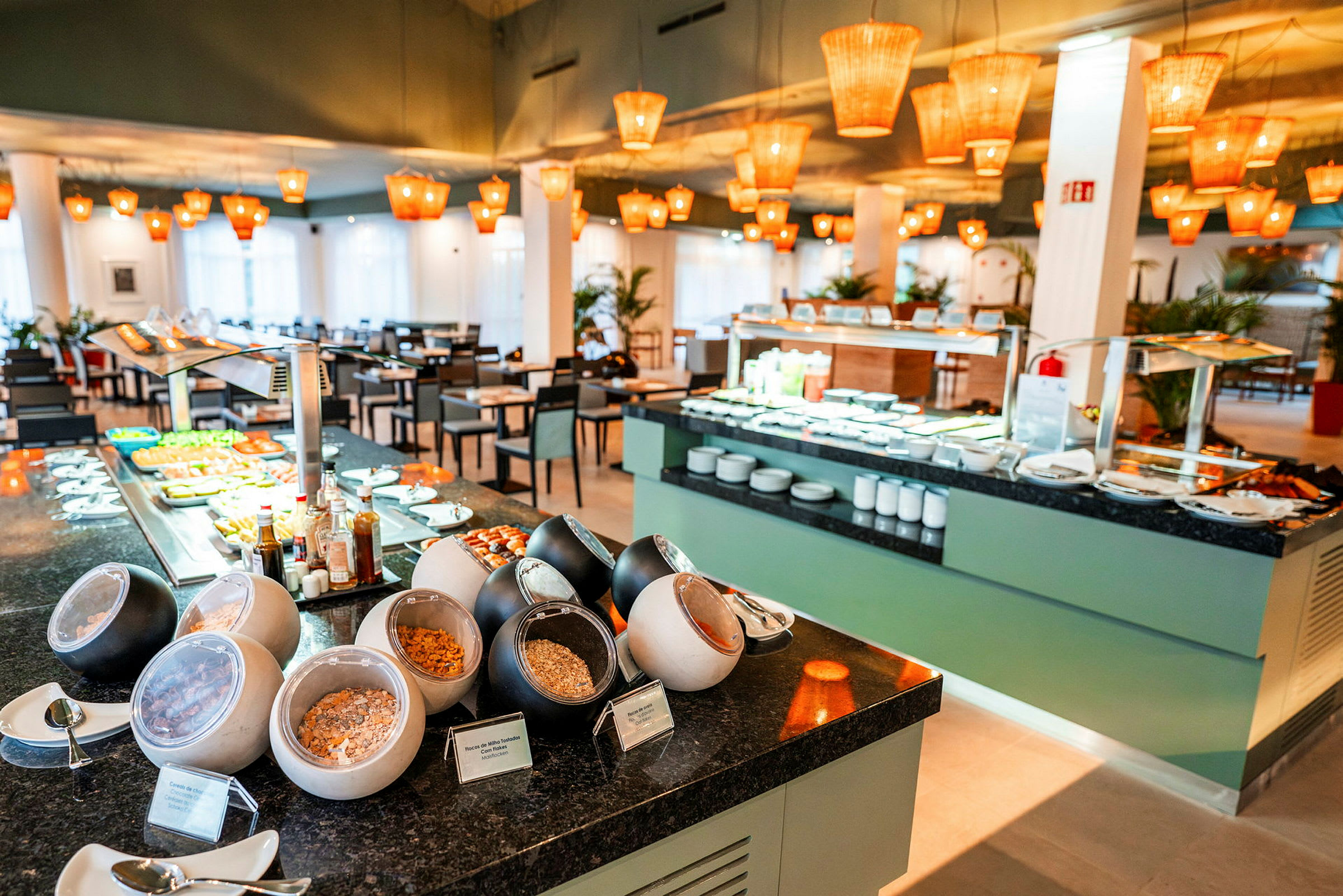 Frokostbuffé med forskjellige stasjoner og sitteplasser i restaurantmiljø. (AI-generert tekst)
