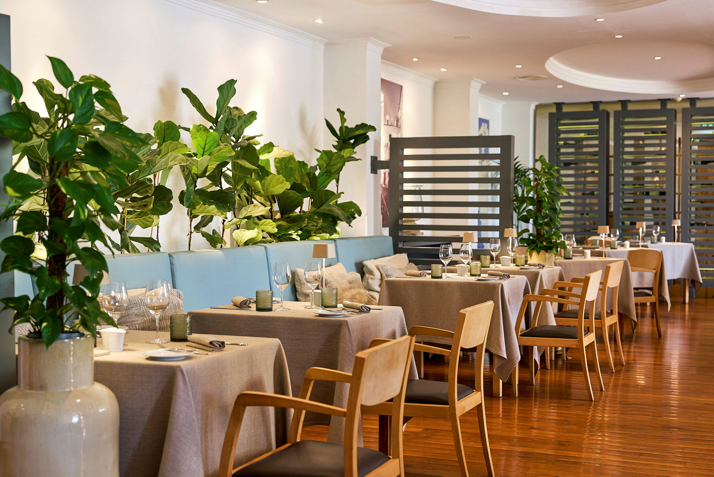 Restaurant med dekkede bord og grønt som dekorasjon. (AI-generert tekst)