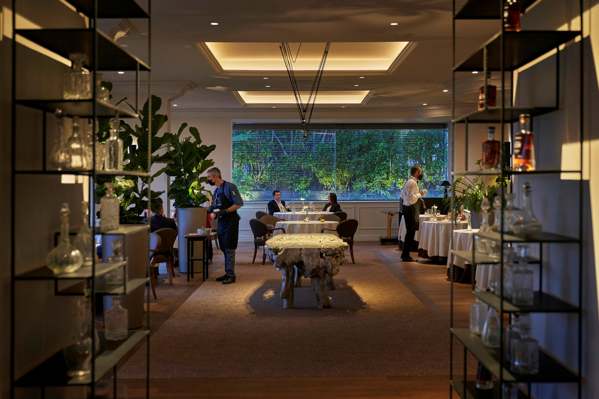 Restaurantmiljø med bord, stoler og planter. (AI-generert tekst)