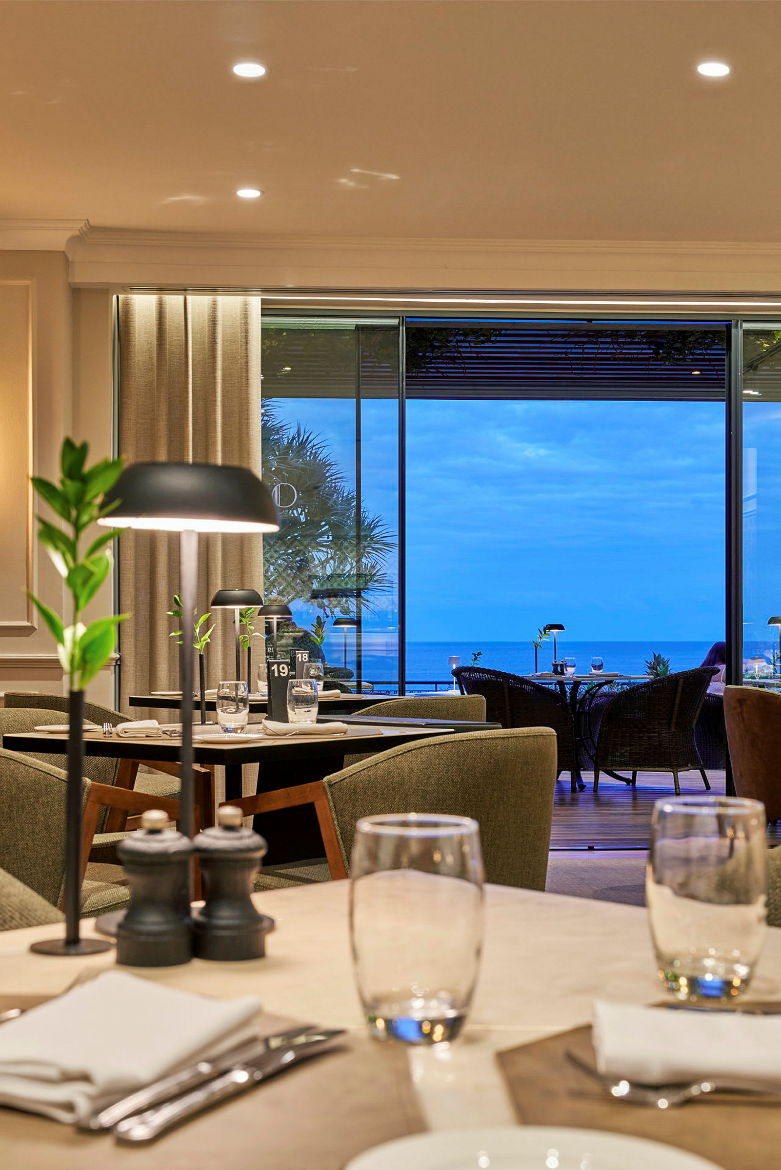 Interiør av en restaurant med dekket bord og utsikt over havet. (AI-generert tekst)