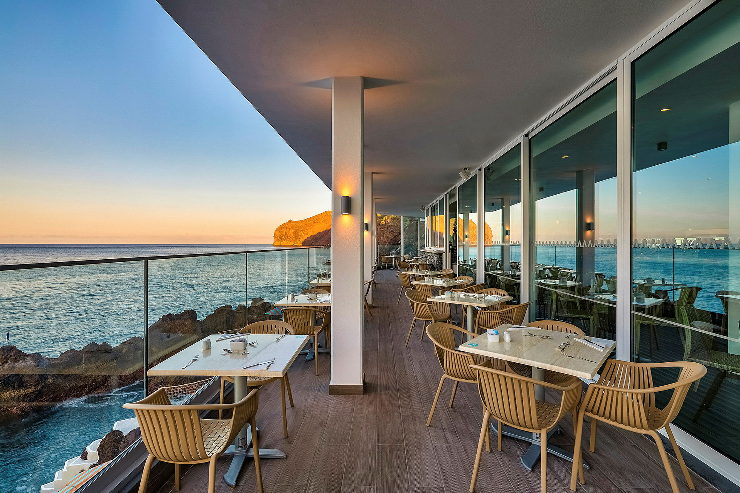 Uteservering med havutsikt og bord på en terrasse. (AI-generert tekst)
