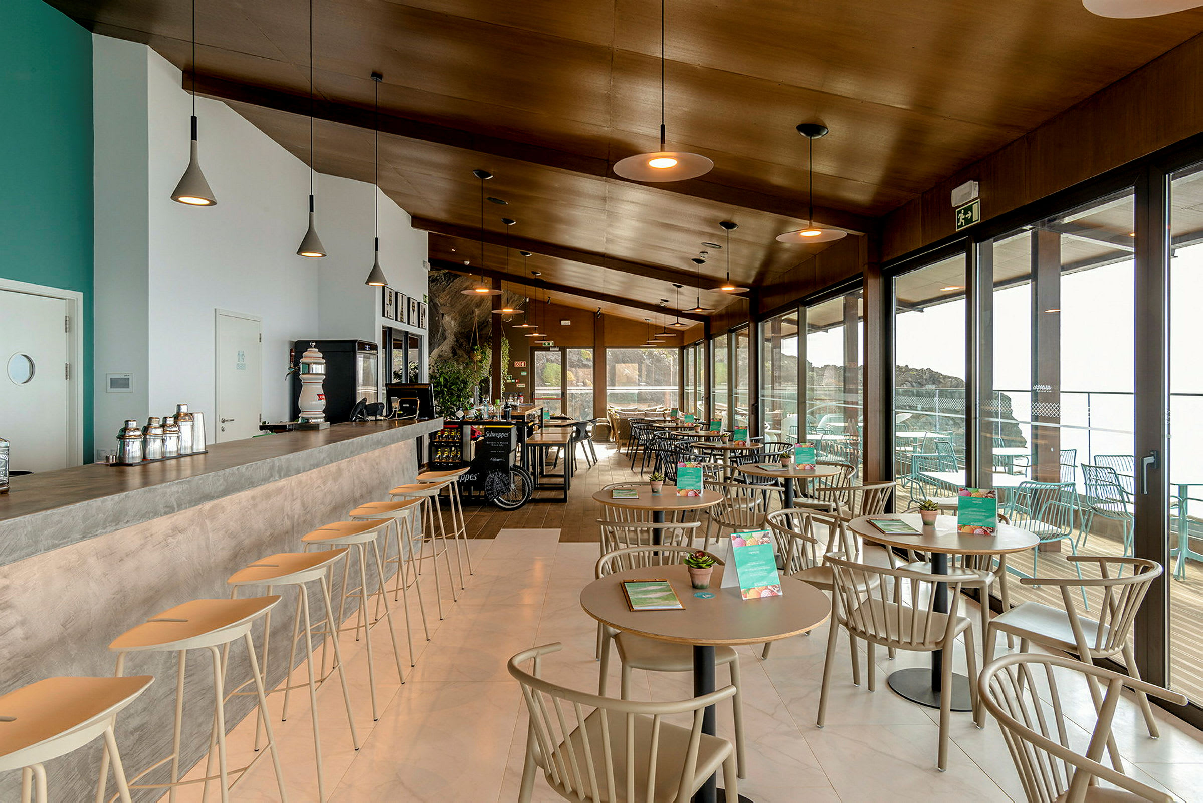 Moderne kafémøbler og bar med store vinduer i bakgrunnen. (AI-generert tekst)