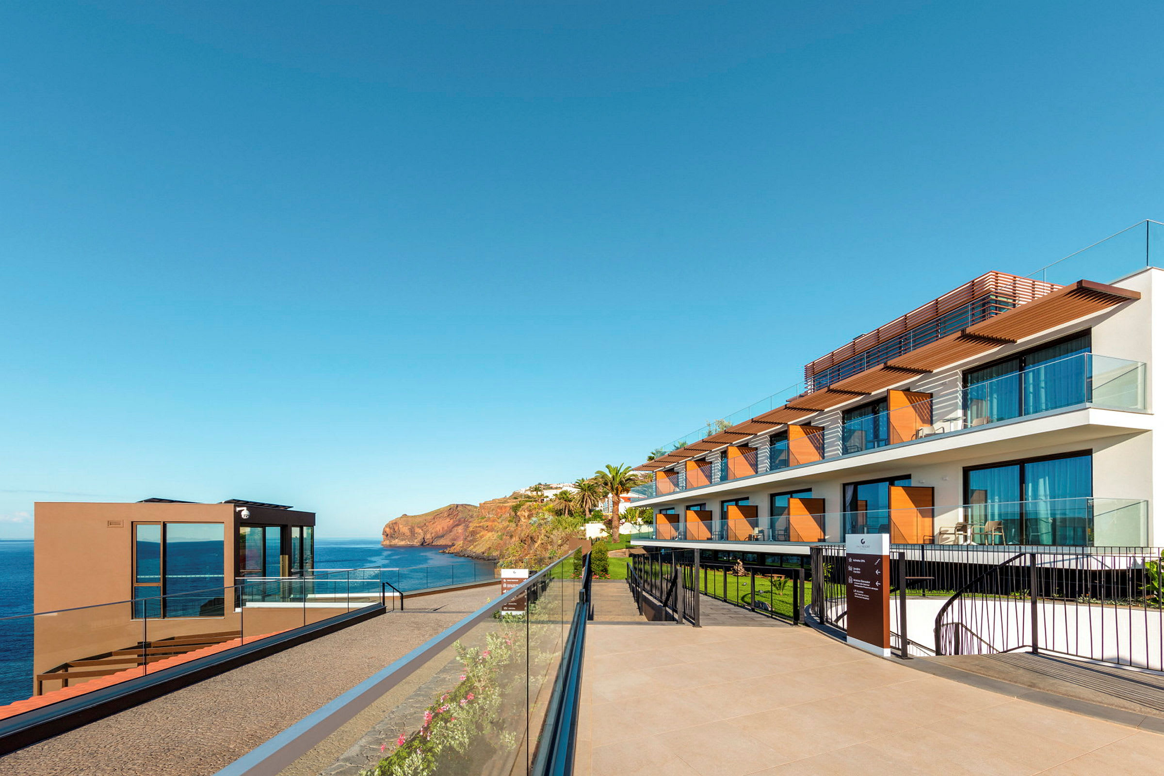 Hotellbygning ved havet under klar blå himmel. (AI-generert tekst)