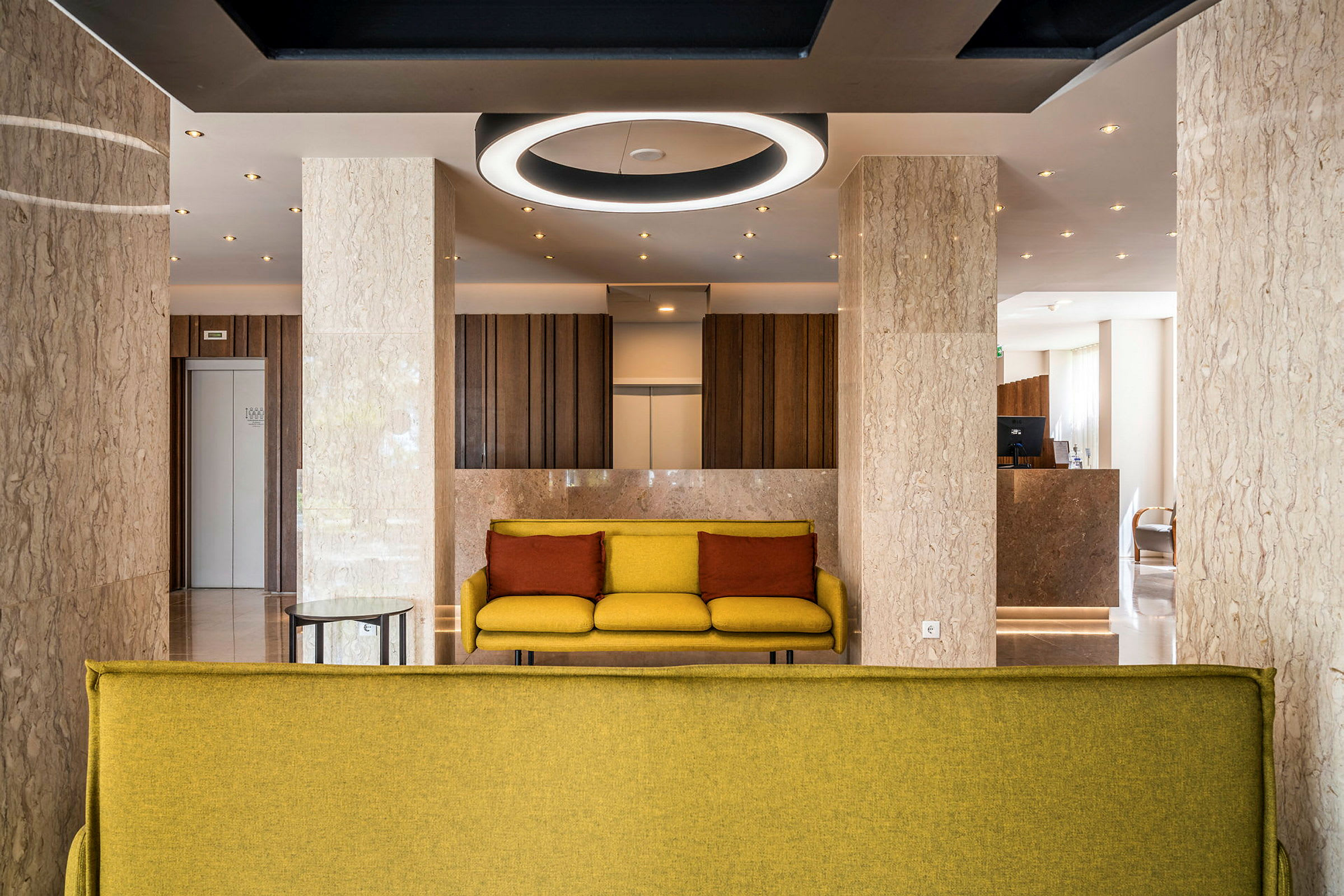 Moderne hotellobby med gule sofaer og marmorvegger. (AI-generert tekst)