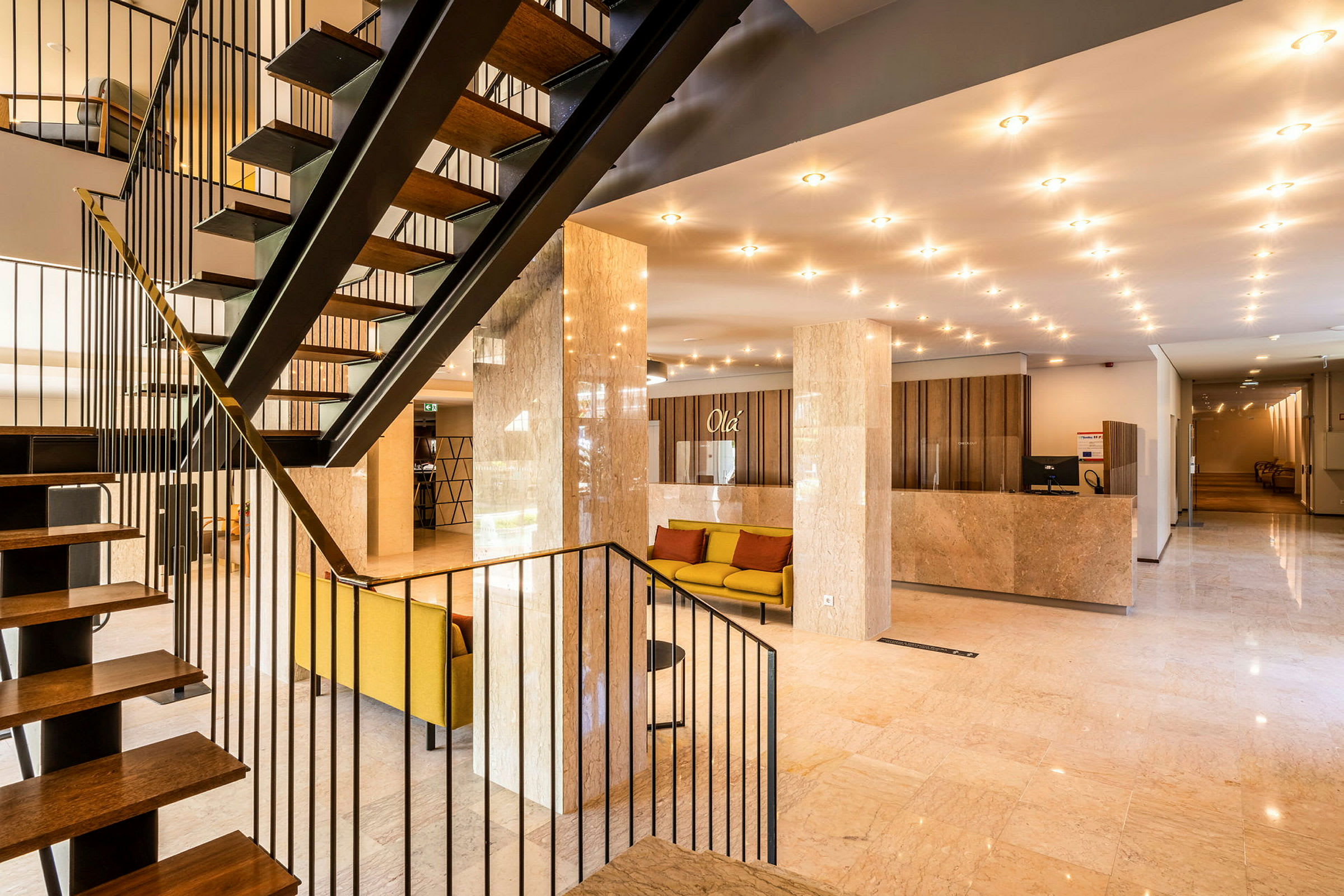 Hotellobby med trapp, sittemøbler og resepsjonsdisk. (AI-generert tekst)