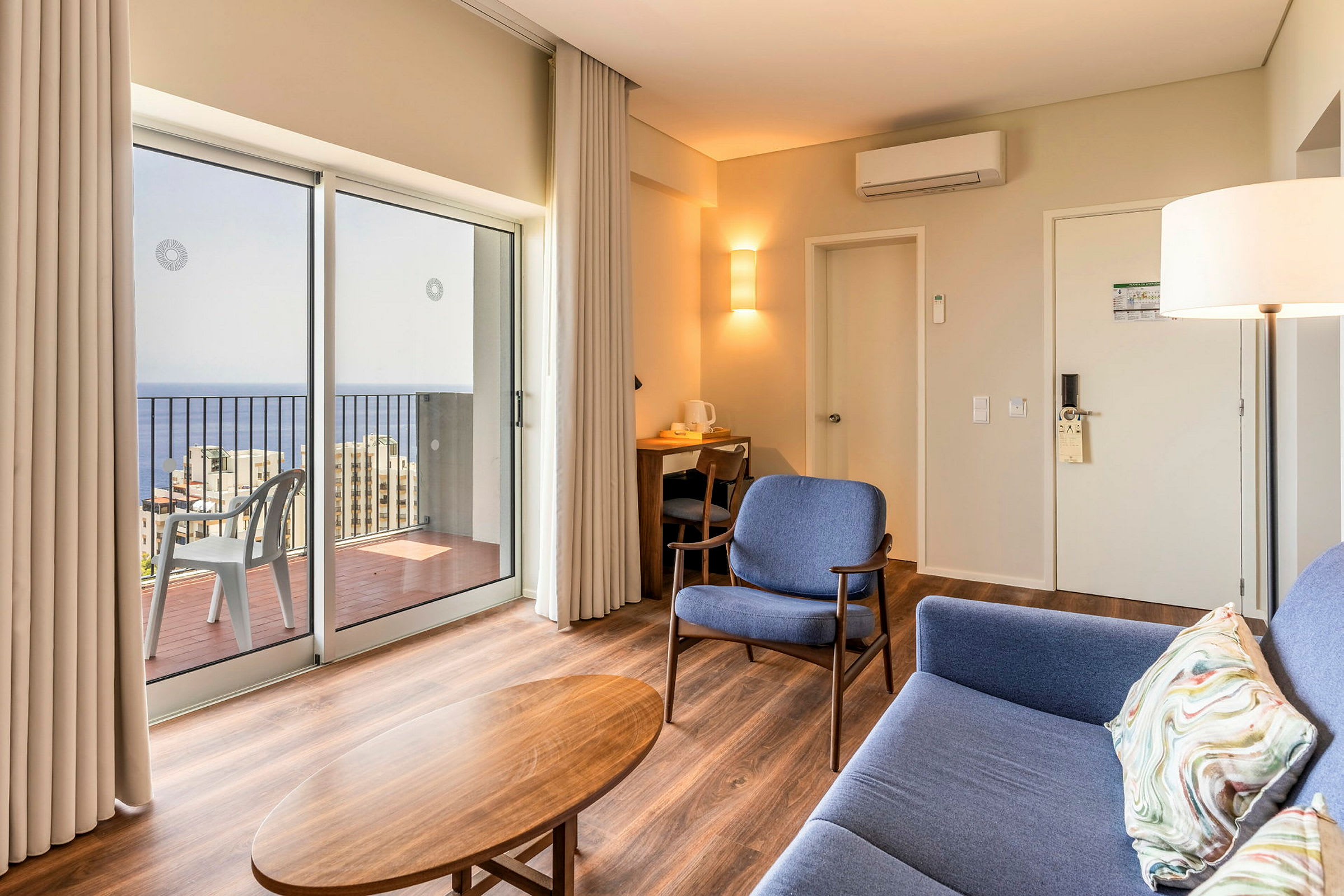 Moderne hotellrom med sitteplasser og utsikt over havet gjennom store vinduer. (AI-generert tekst)