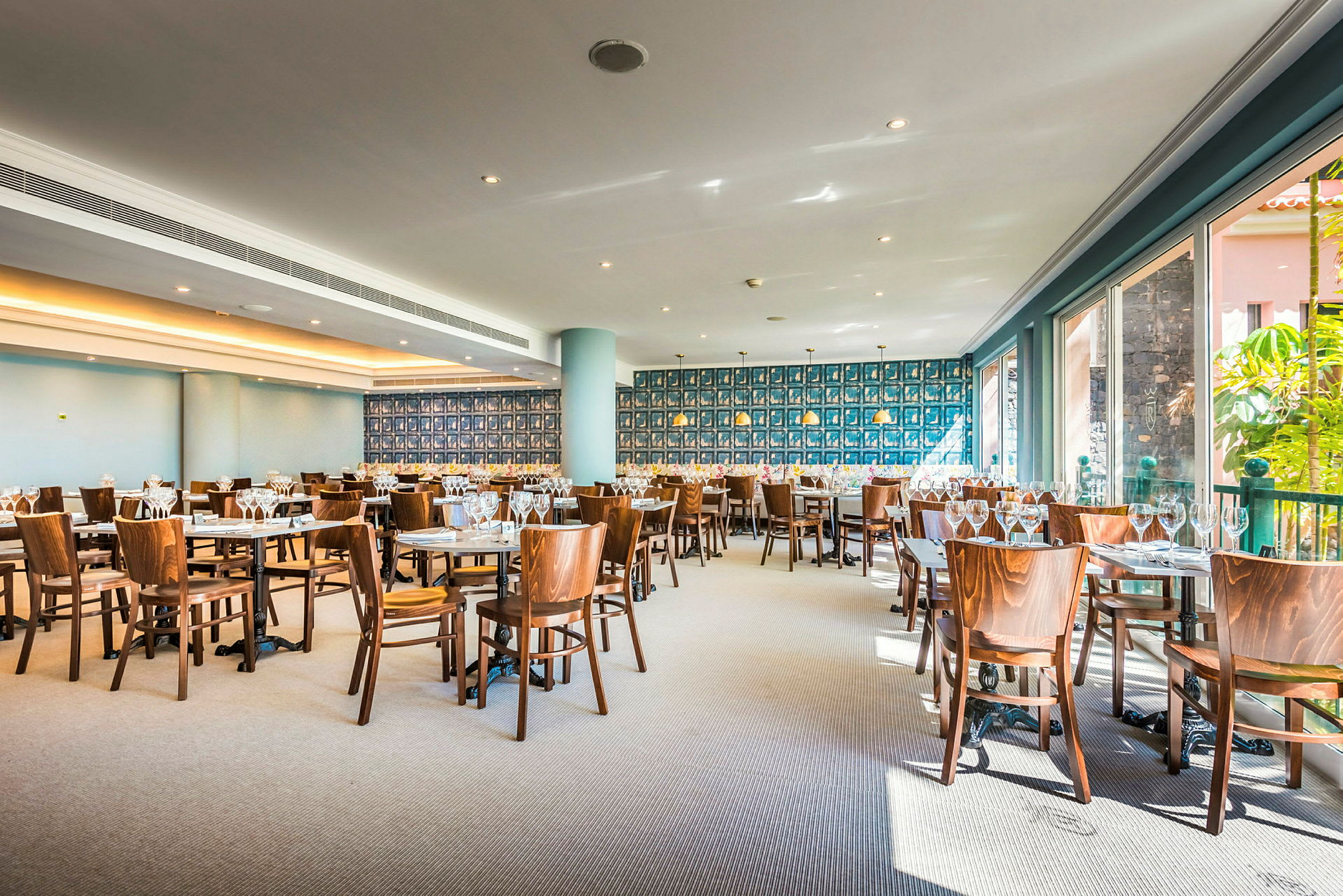 En restaurant med bord og trestoler, dekorert med flere vinglass. (AI-generert tekst)