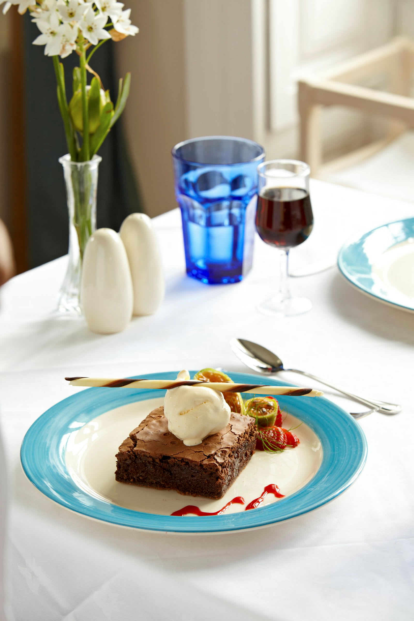 En tallerken med brownie og iskrem, dekorert med frukt og saus. (AI-generert tekst)