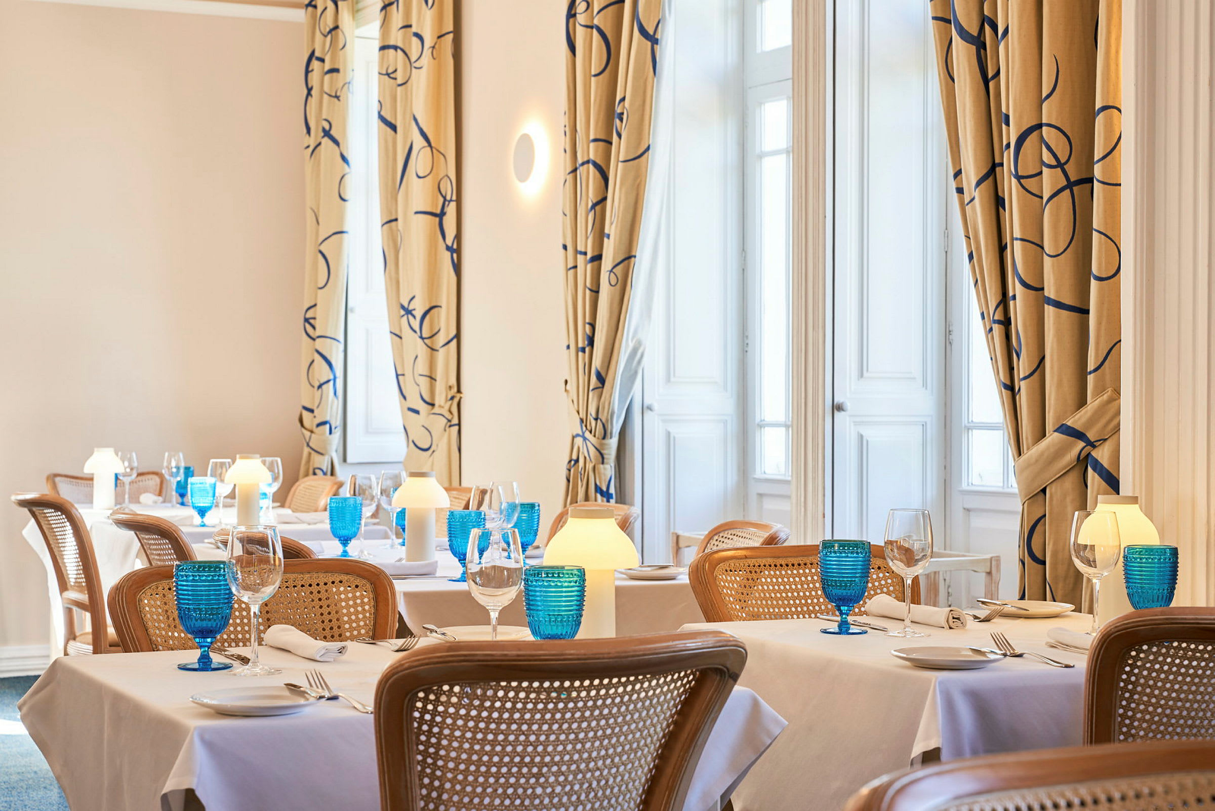 Bilde av en elegant restaurant med dekkede bord, blå glass og varm belysning. (AI-generert tekst)