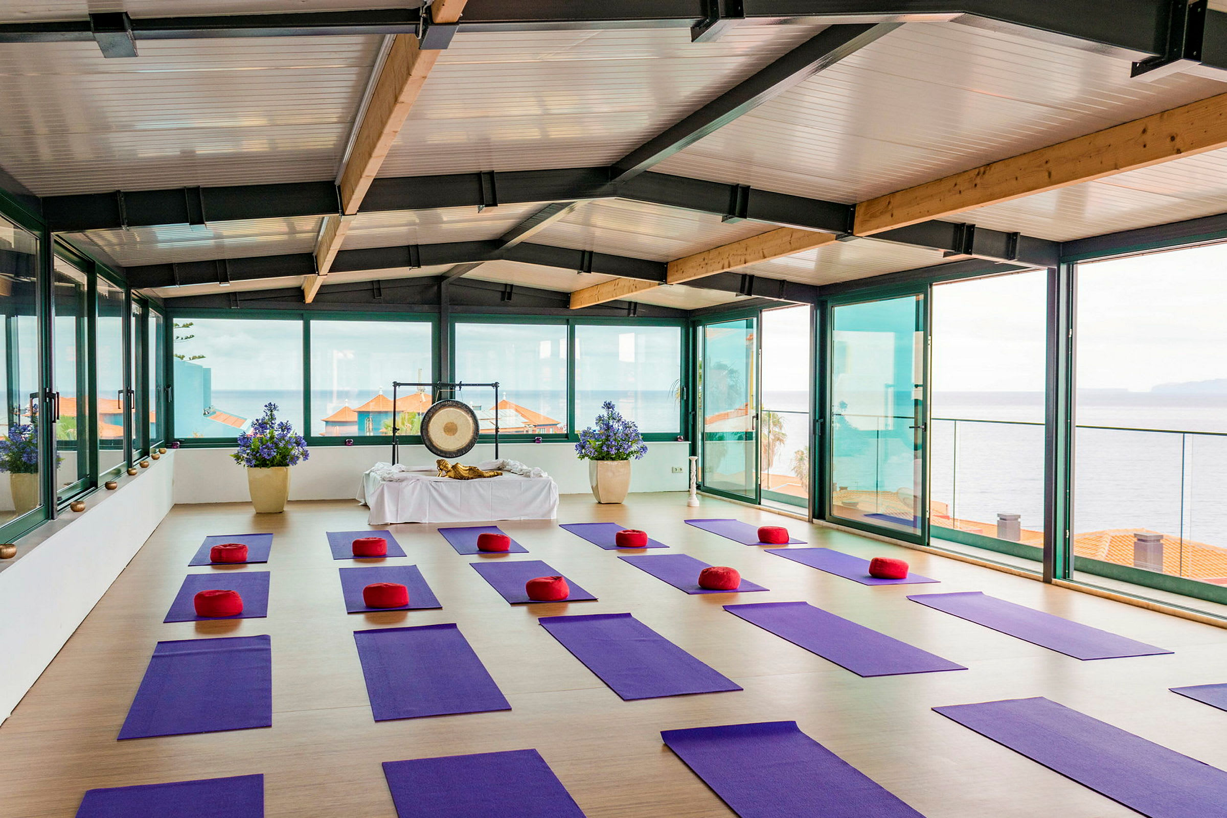 Et rom med gulvmatter og puter for yoga med utsikt mot havet. (AI-generert tekst)